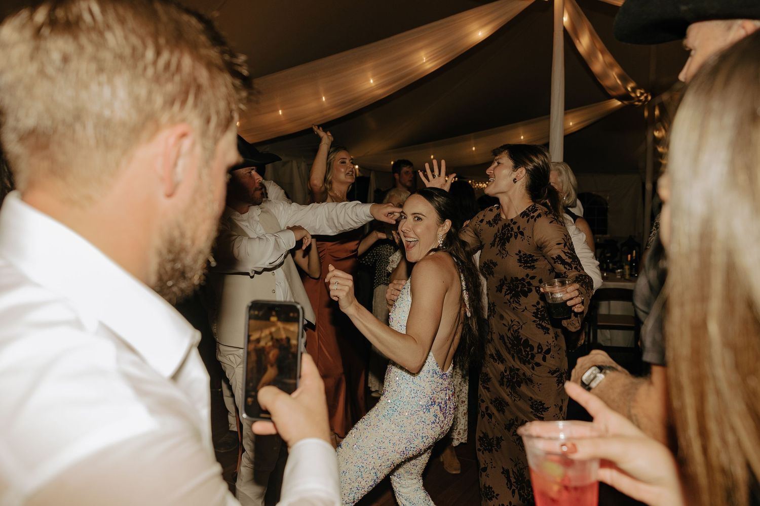 Lively crowd of people dancing and celebrating at a dimly lit party venue.