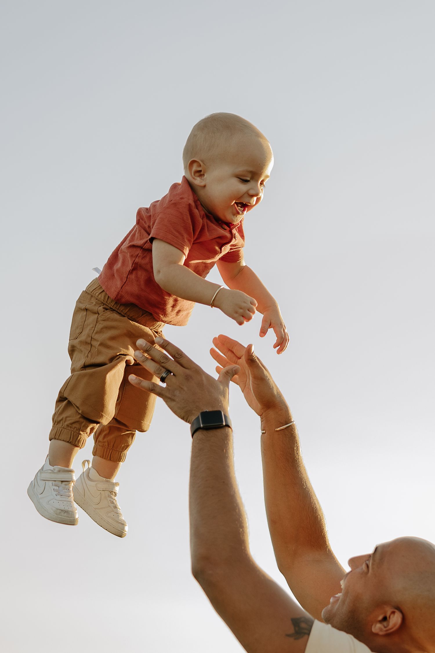 Parent lifting baby in the air against white background in sequence shots.