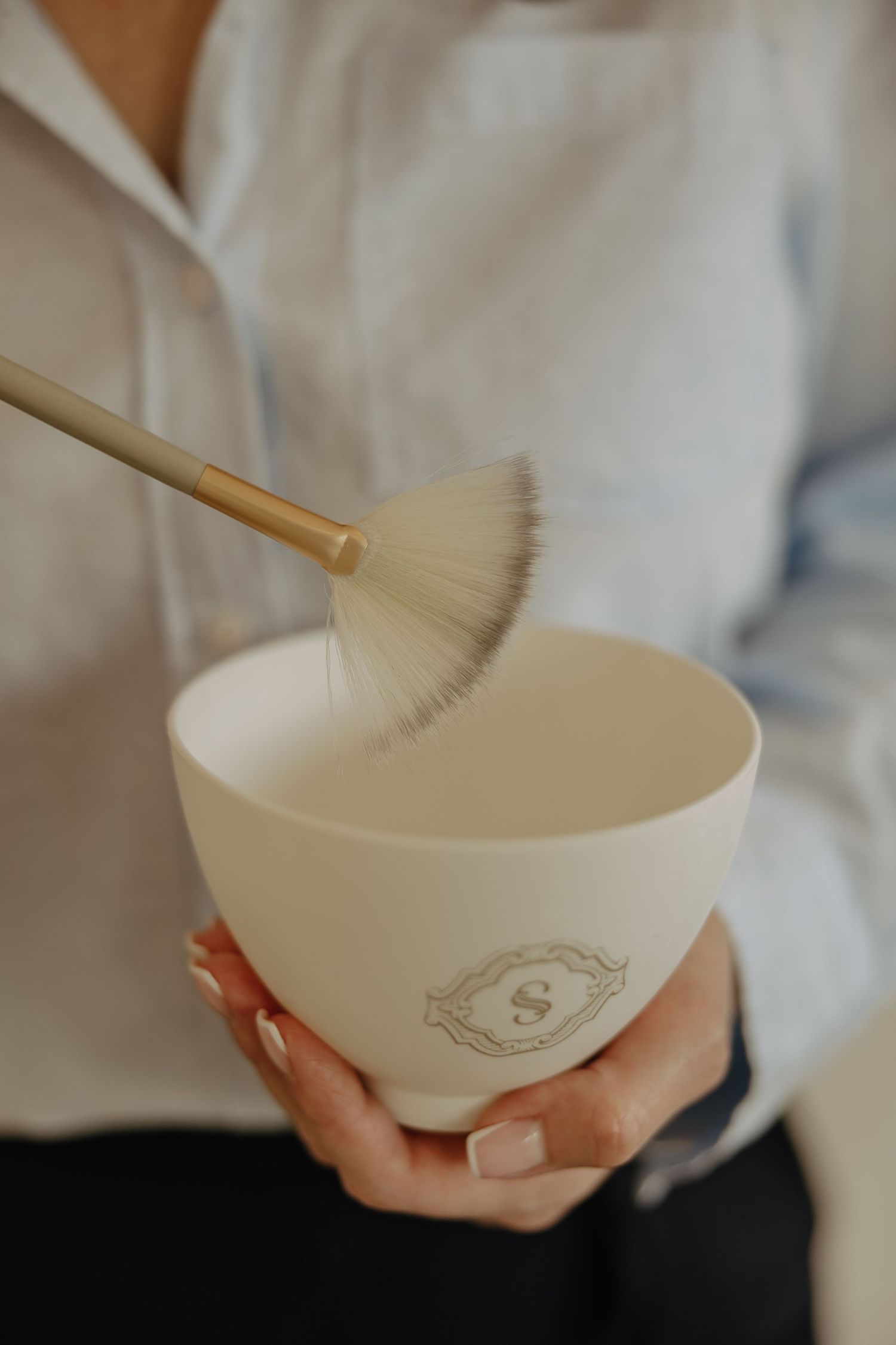 Close-up shots of hands holding and whisking in a decorative white ceramic bowl.