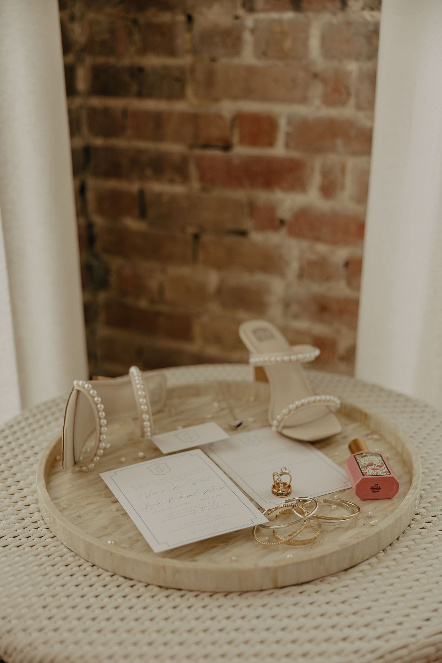 Wedding rings and jewelry arranged on a white textured surface against a rustic brick wall background.