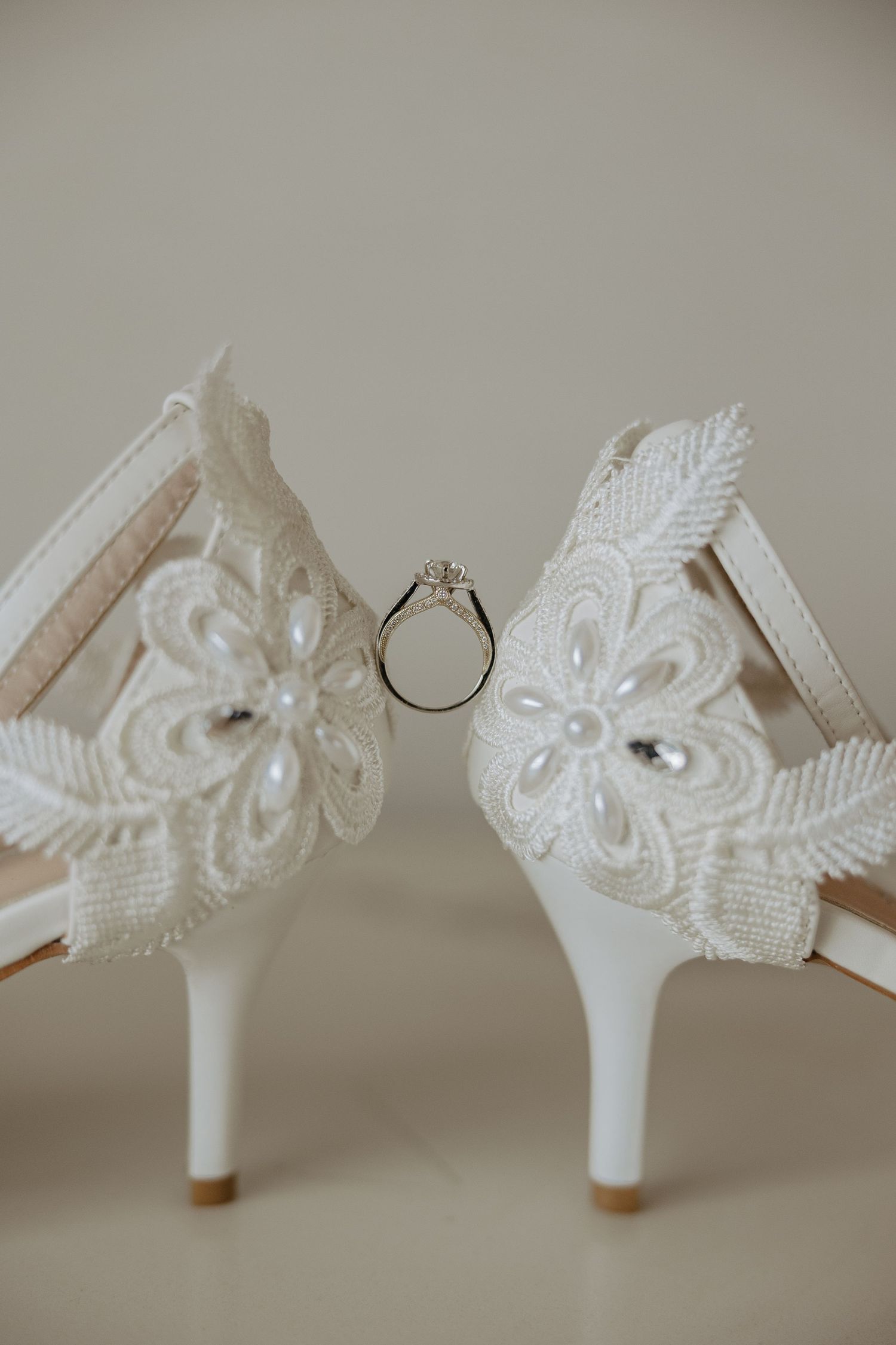 Close-up sequence of delicate white lace and pearl embellishments on a bridal shoe heel.