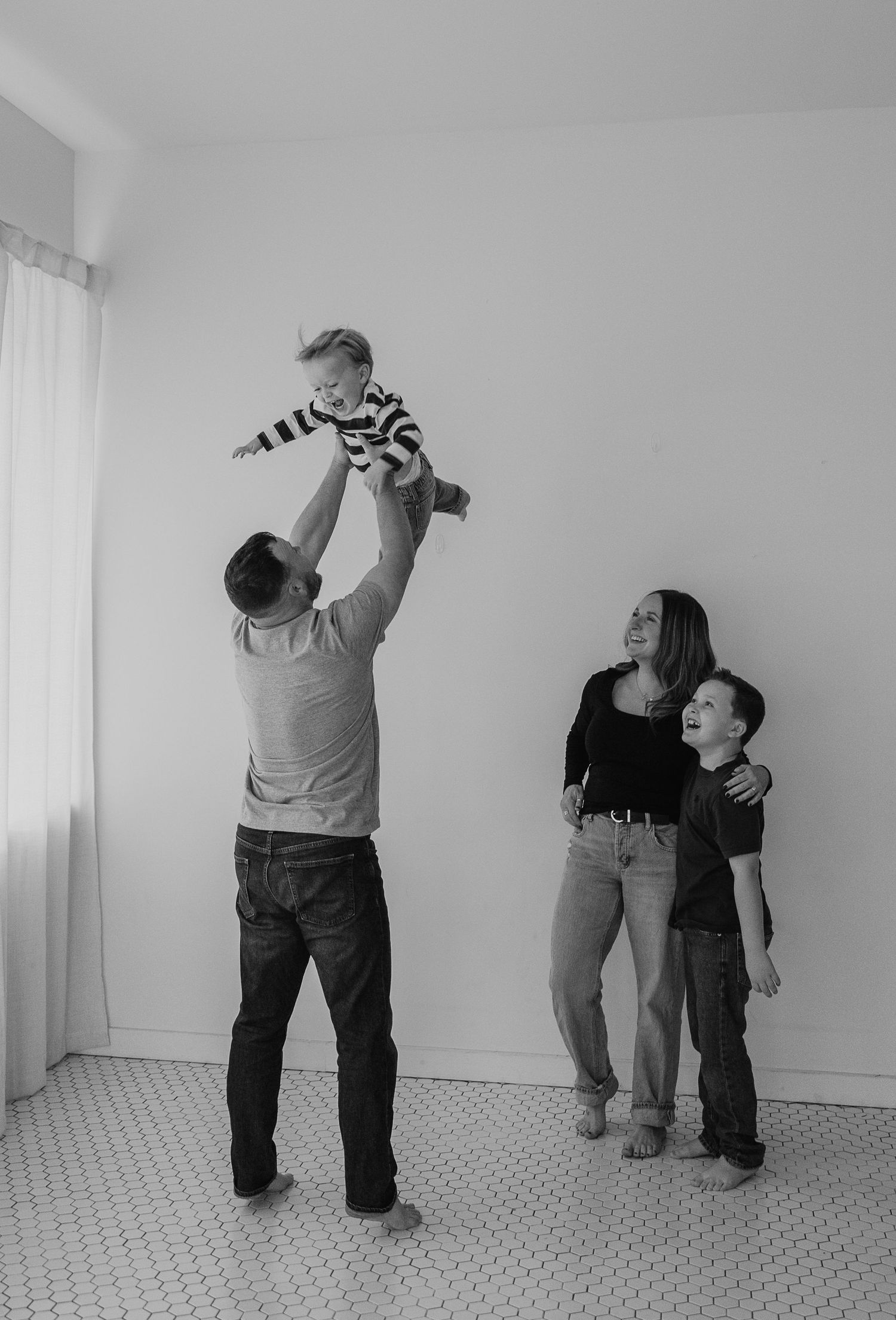 Series of silhouettes showing parent and child playing together against a white wall with tiled floor.