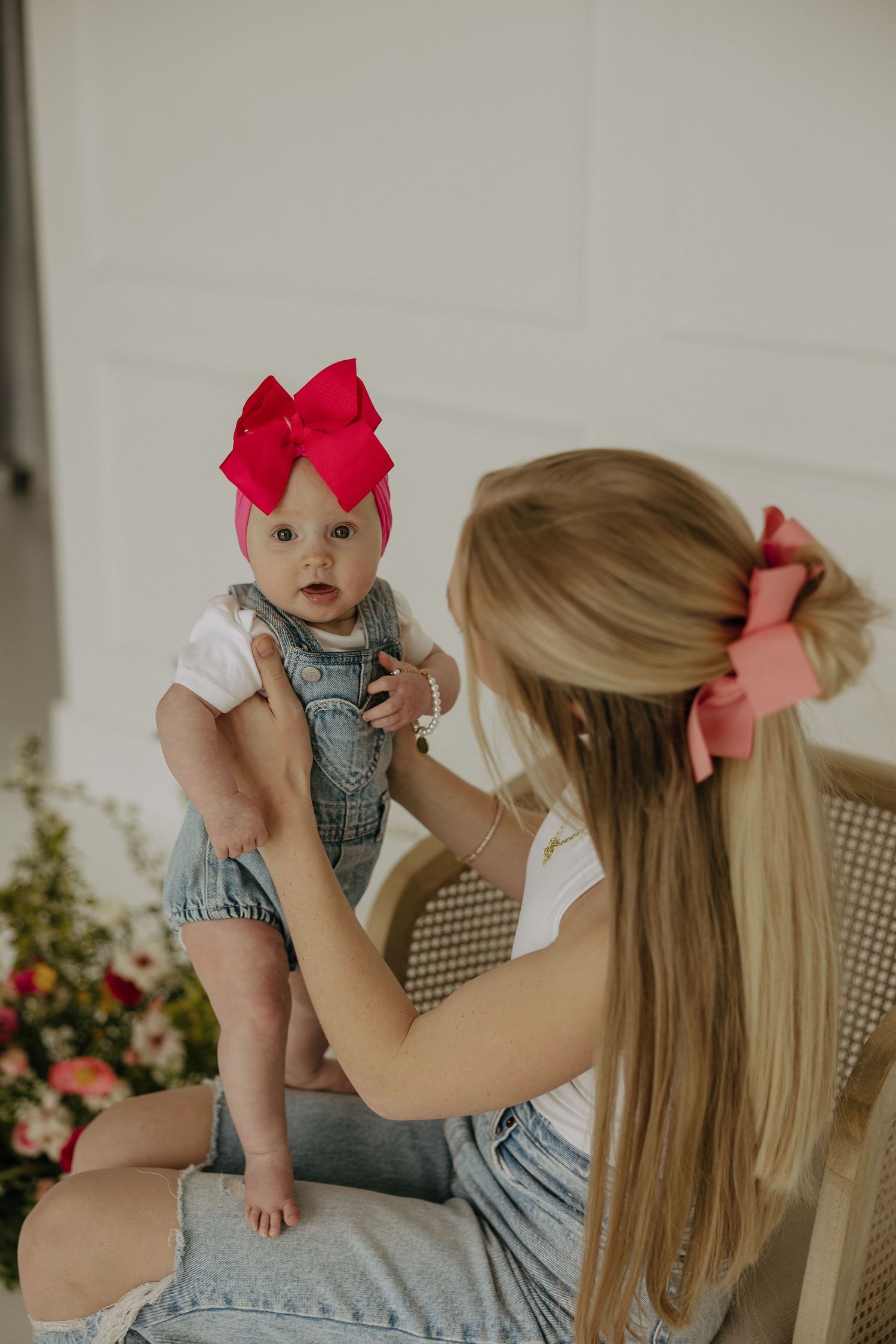 Candid moments captured against a light wall with pink floral arrangements.