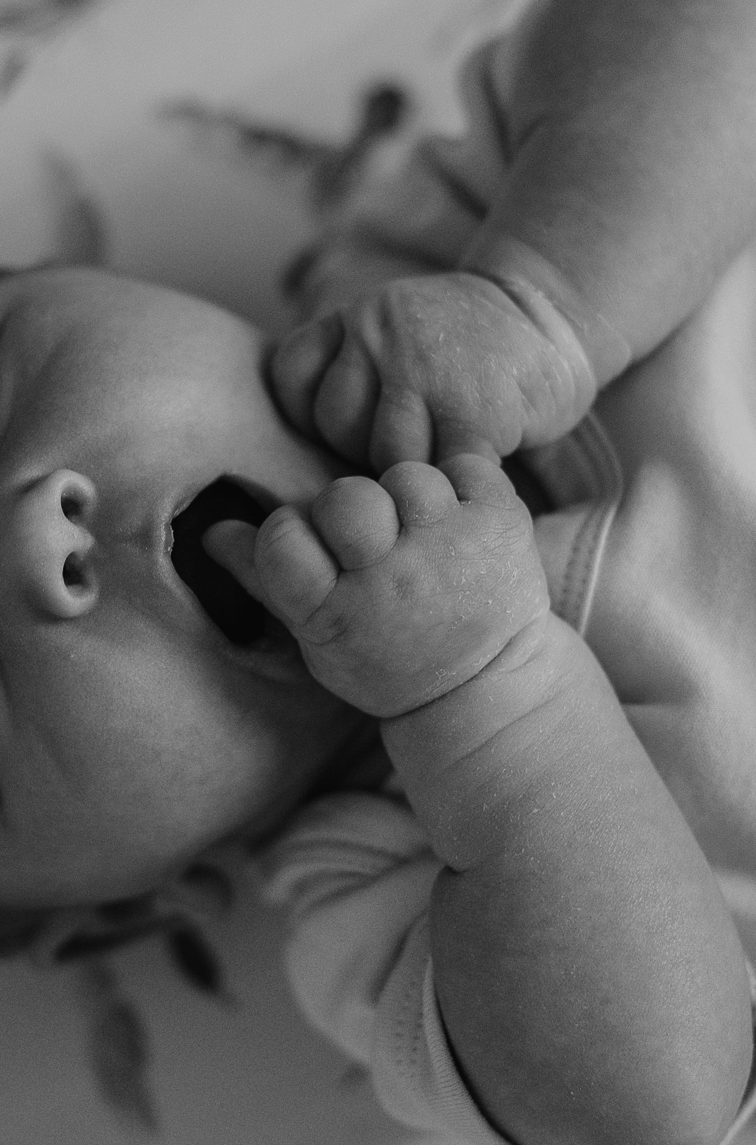 Artistic black and white close-up of a baby's tiny fingers and hands.