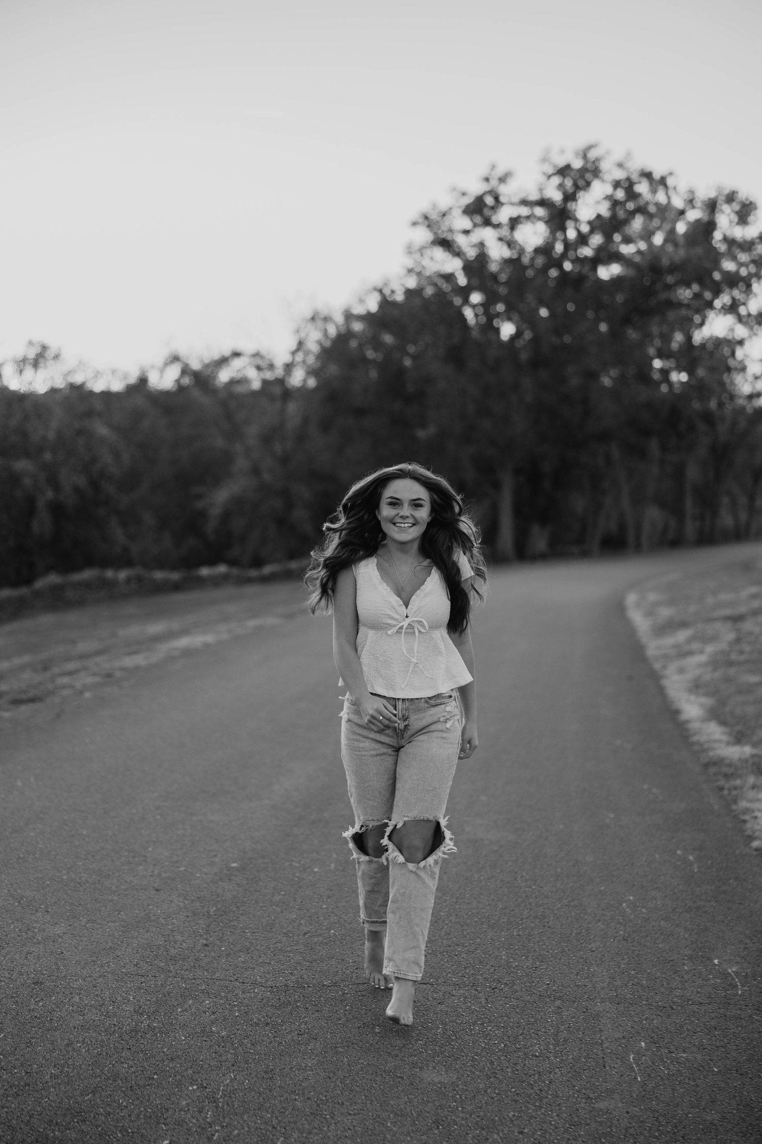 Black and white photo of someone running playfully down a path outdoors.