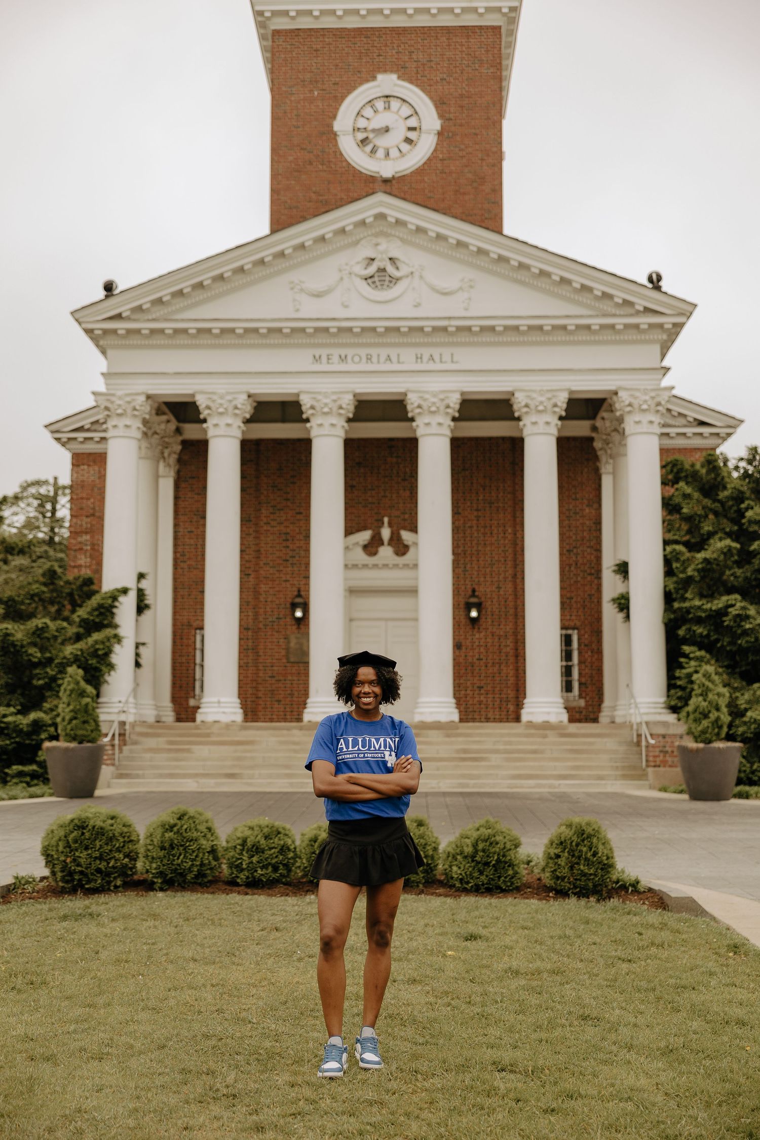 Stately brick and white memorial hall with classical columns and architectural details on a grassy lawn.
