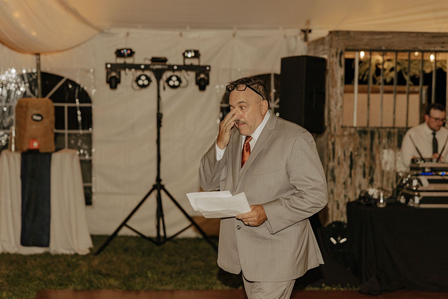 Wedding guests dancing and celebrating under a white tent with festive lighting.