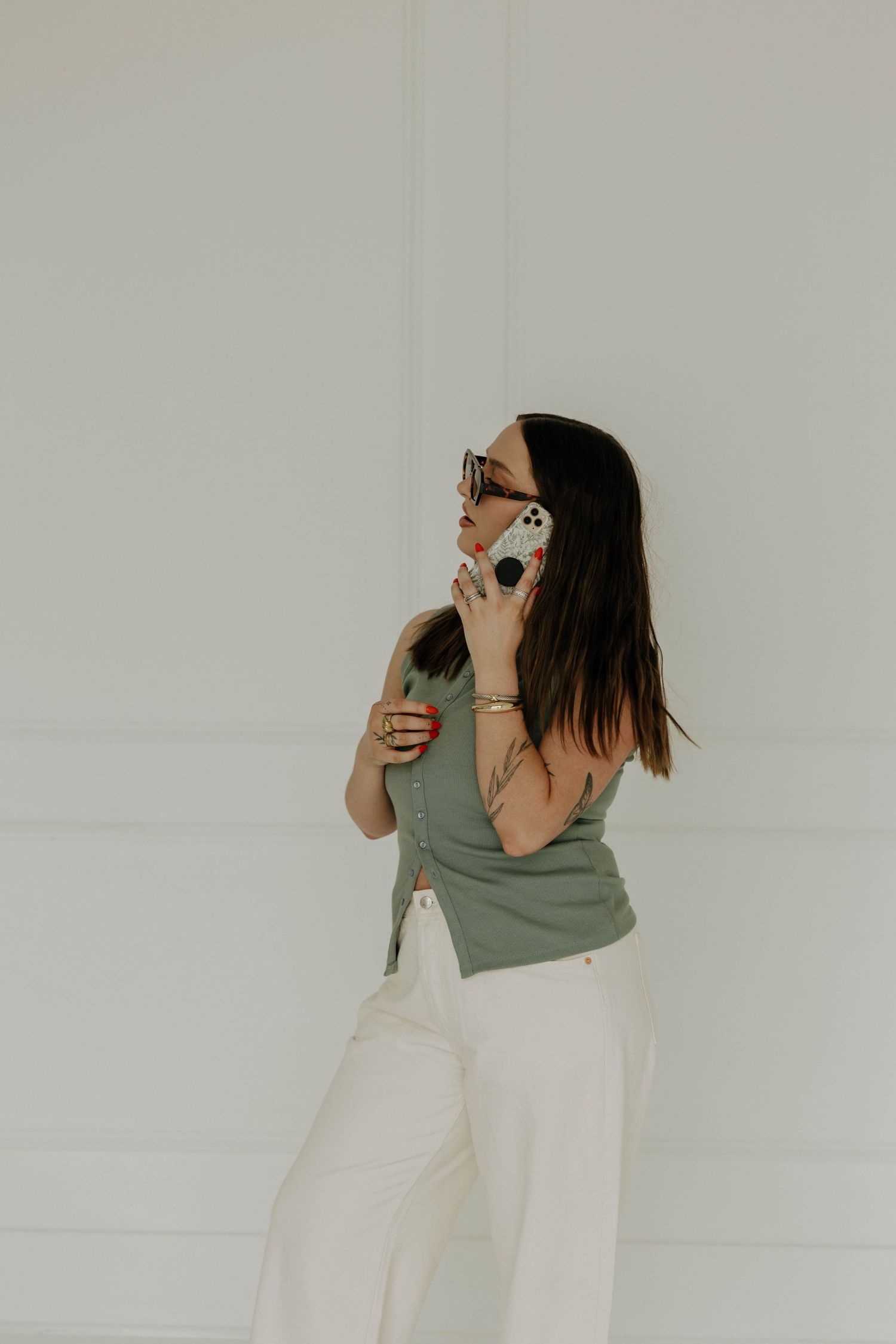 A person in sage green and white poses dramatically with beauty products.