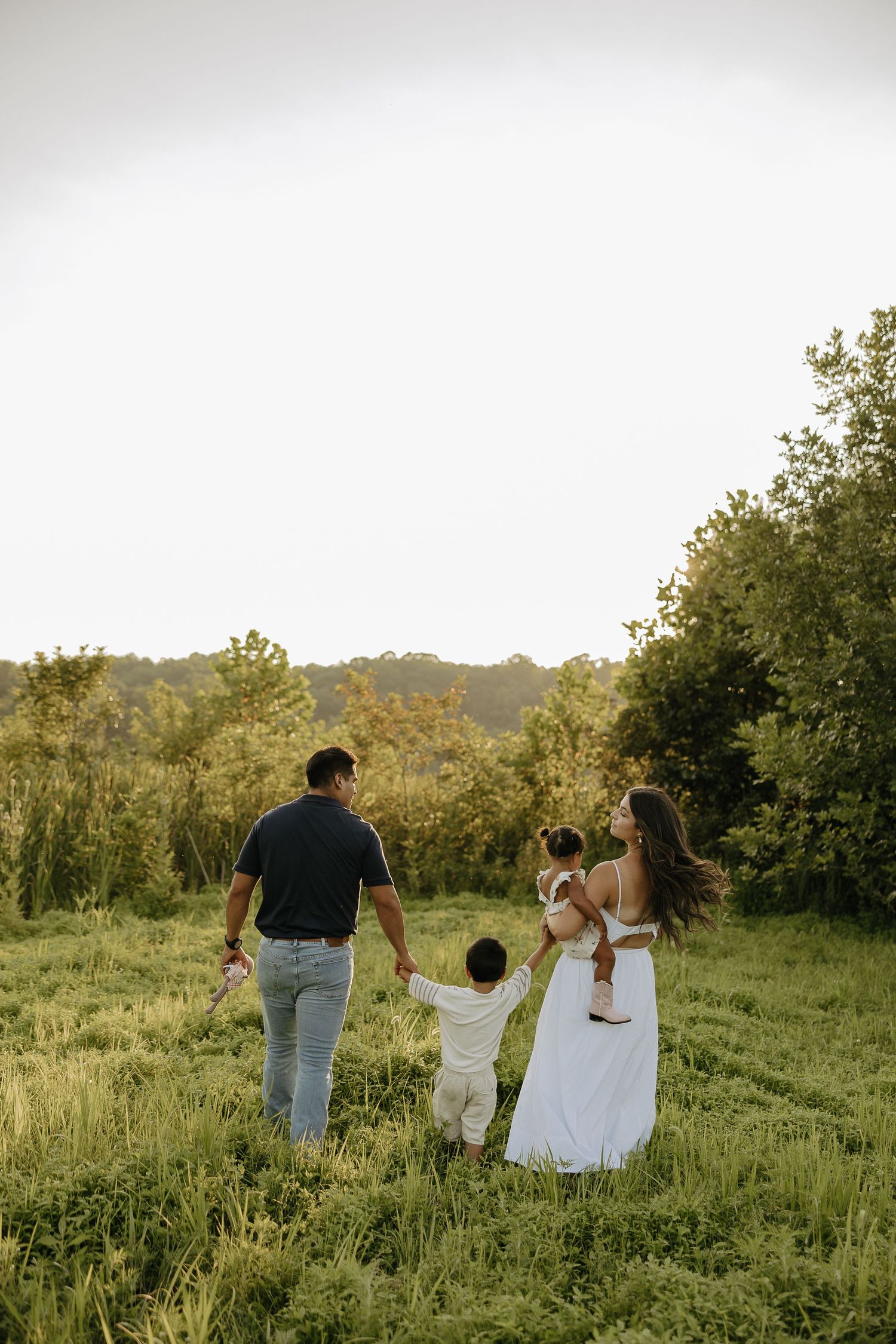 Family walking together through a scenic hillside meadow.