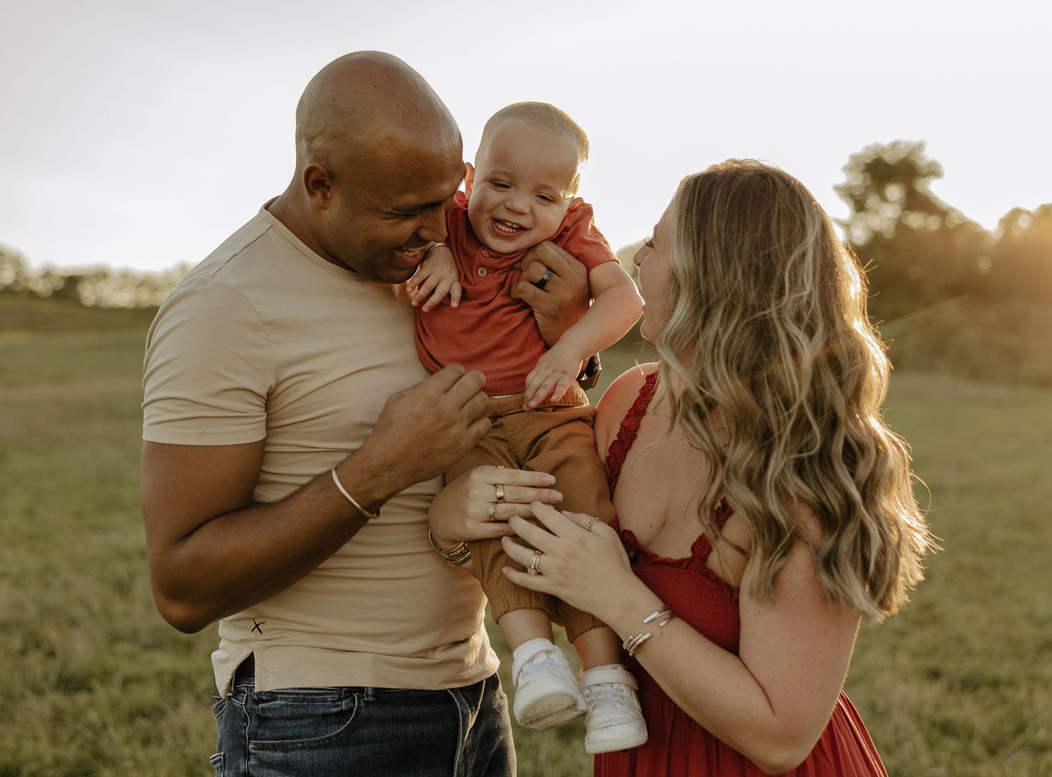 Family sharing tender moments together in golden sunlit field.