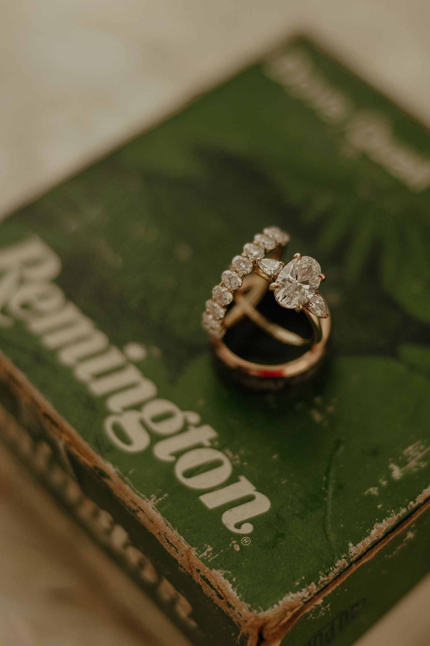 Diamond engagement ring displayed on a vintage green book with worn edges.
