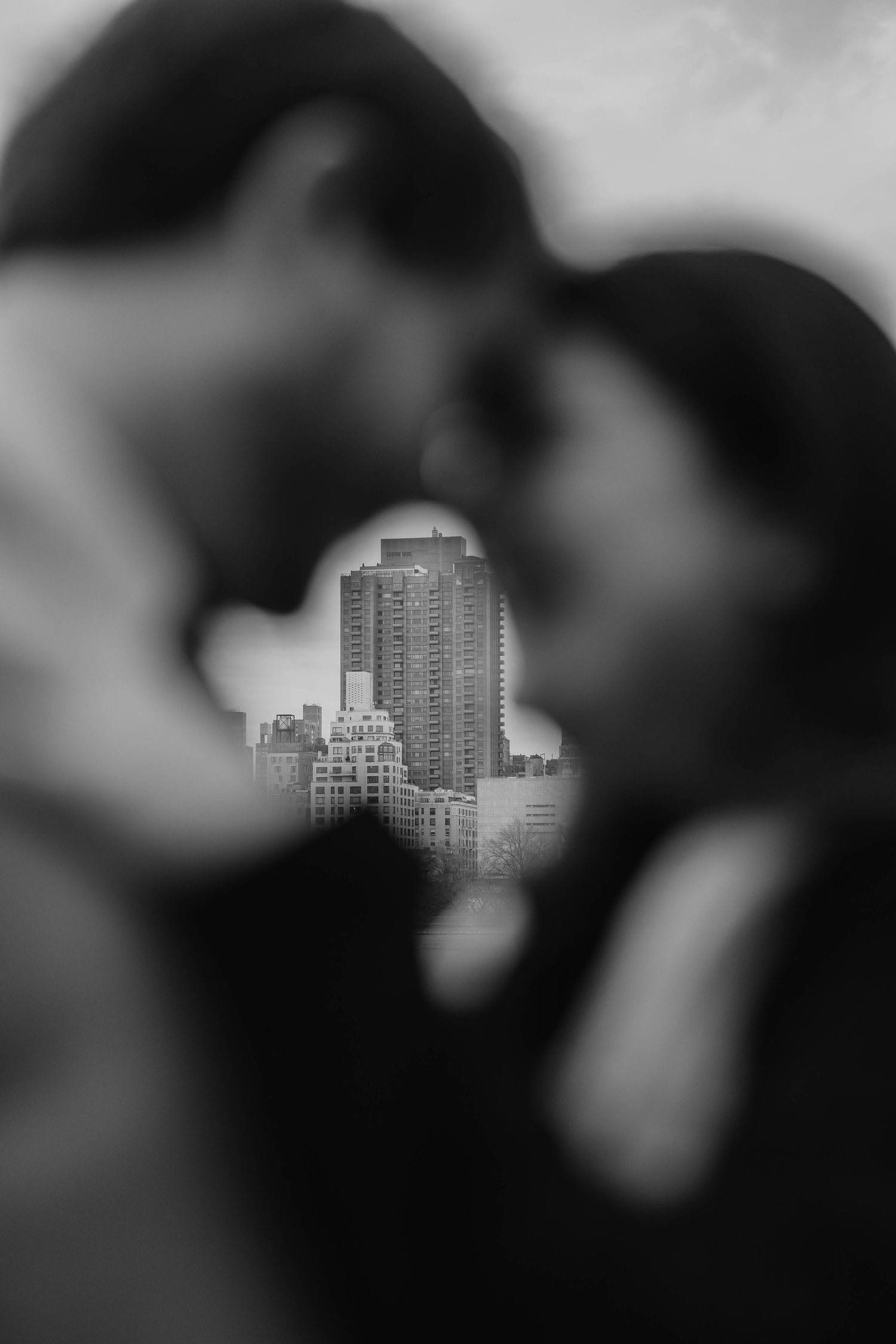 Black and white cityscape with urban buildings visible through a blurred foreground.