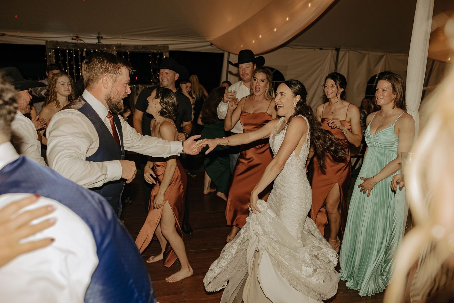 Wedding guests dance and celebrate on a crowded reception dance floor.