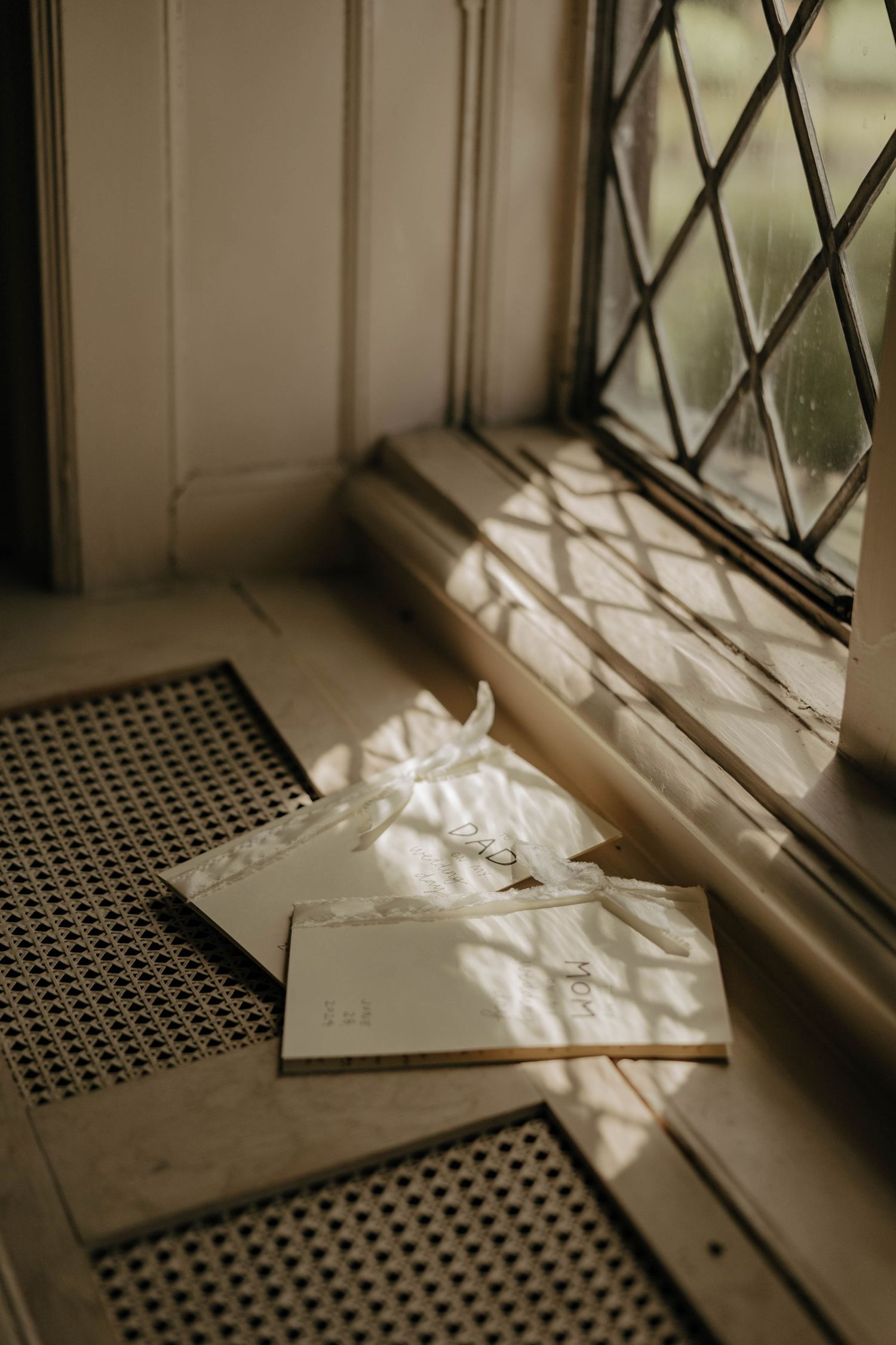 Sunlight casts diamond patterns through leaded glass windows onto a textured surface in a moody sepia-toned scene.