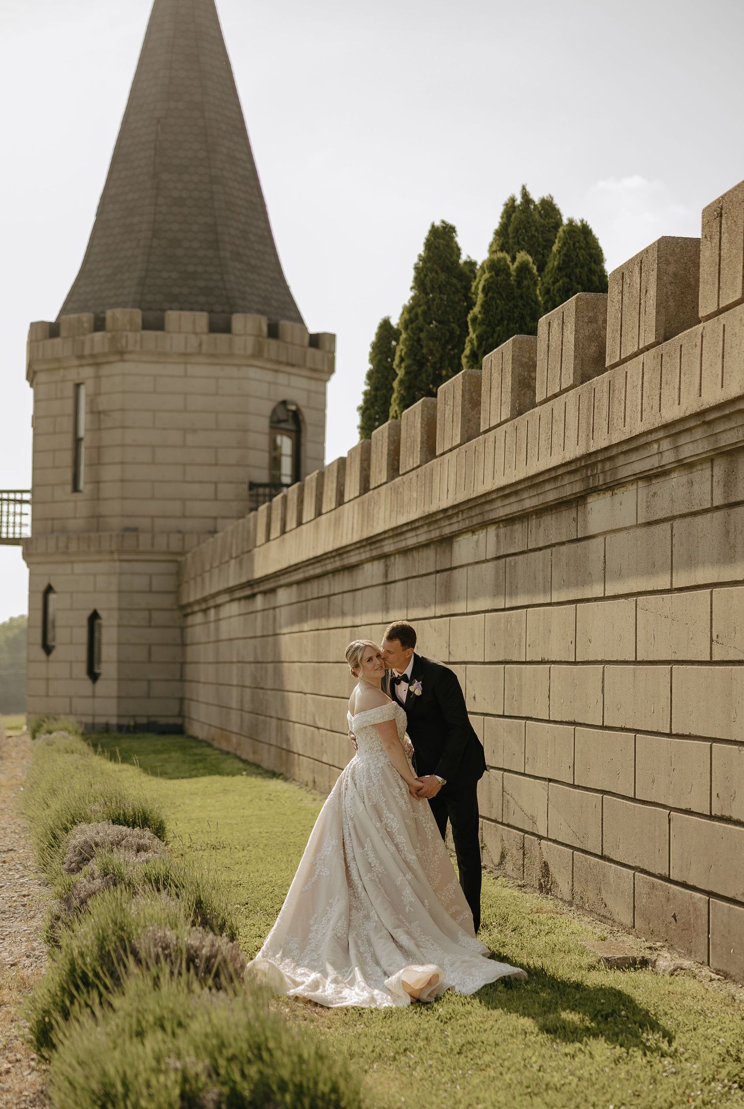 Romantic wedding photos taken against stone castle walls and towers with lavender gardens.