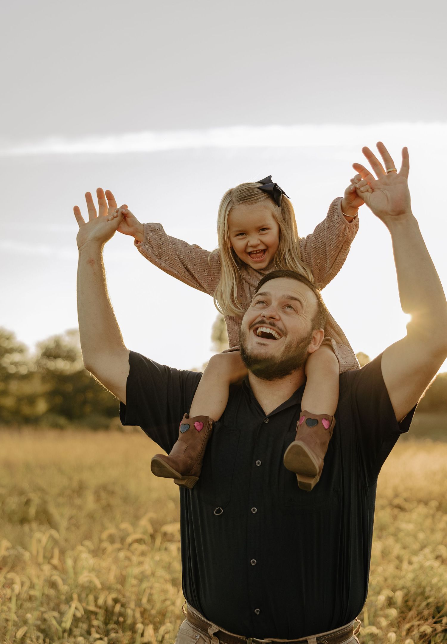 Joyful people raise their hands high in a sunlit field, expressing pure happiness and freedom.