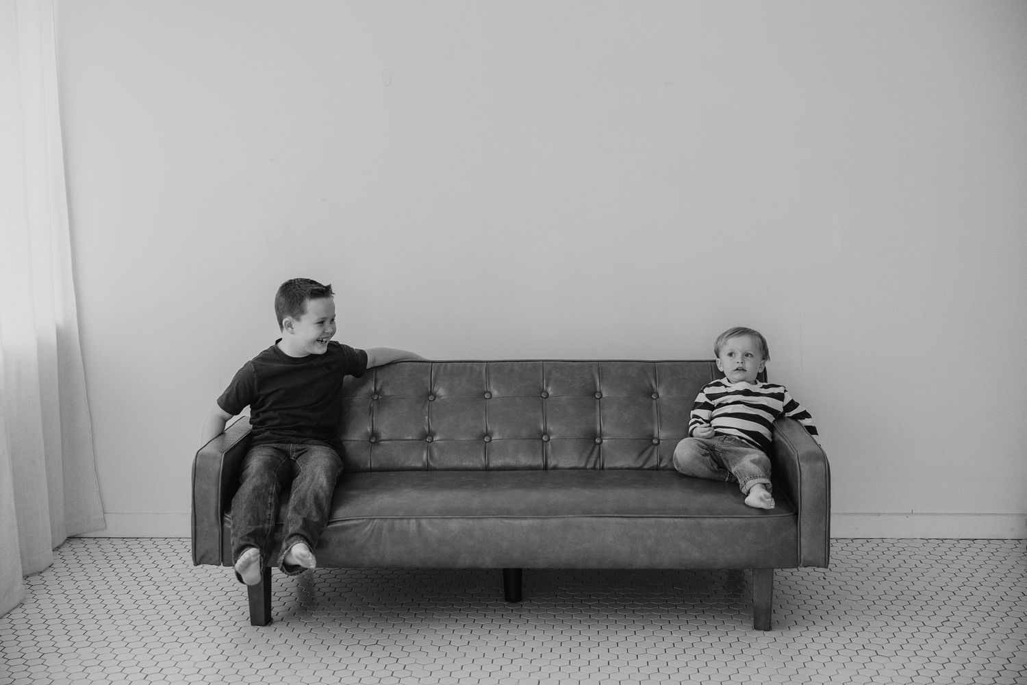 A person lies on a couch in different positions shown in a sequence of black and white photographs.