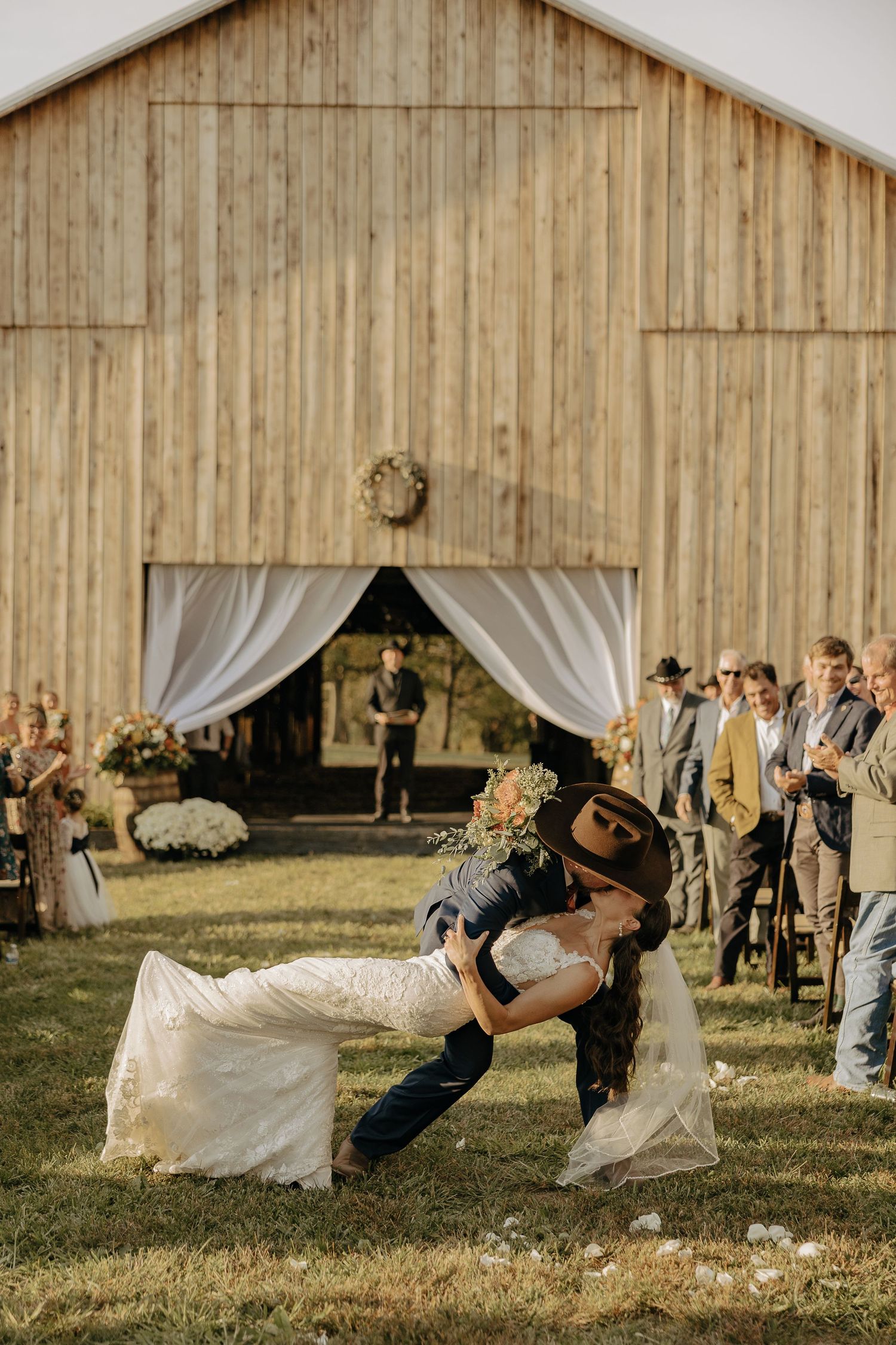 A playful wedding sequence shows a couple dipping in front of a rustic barn with white drapes.