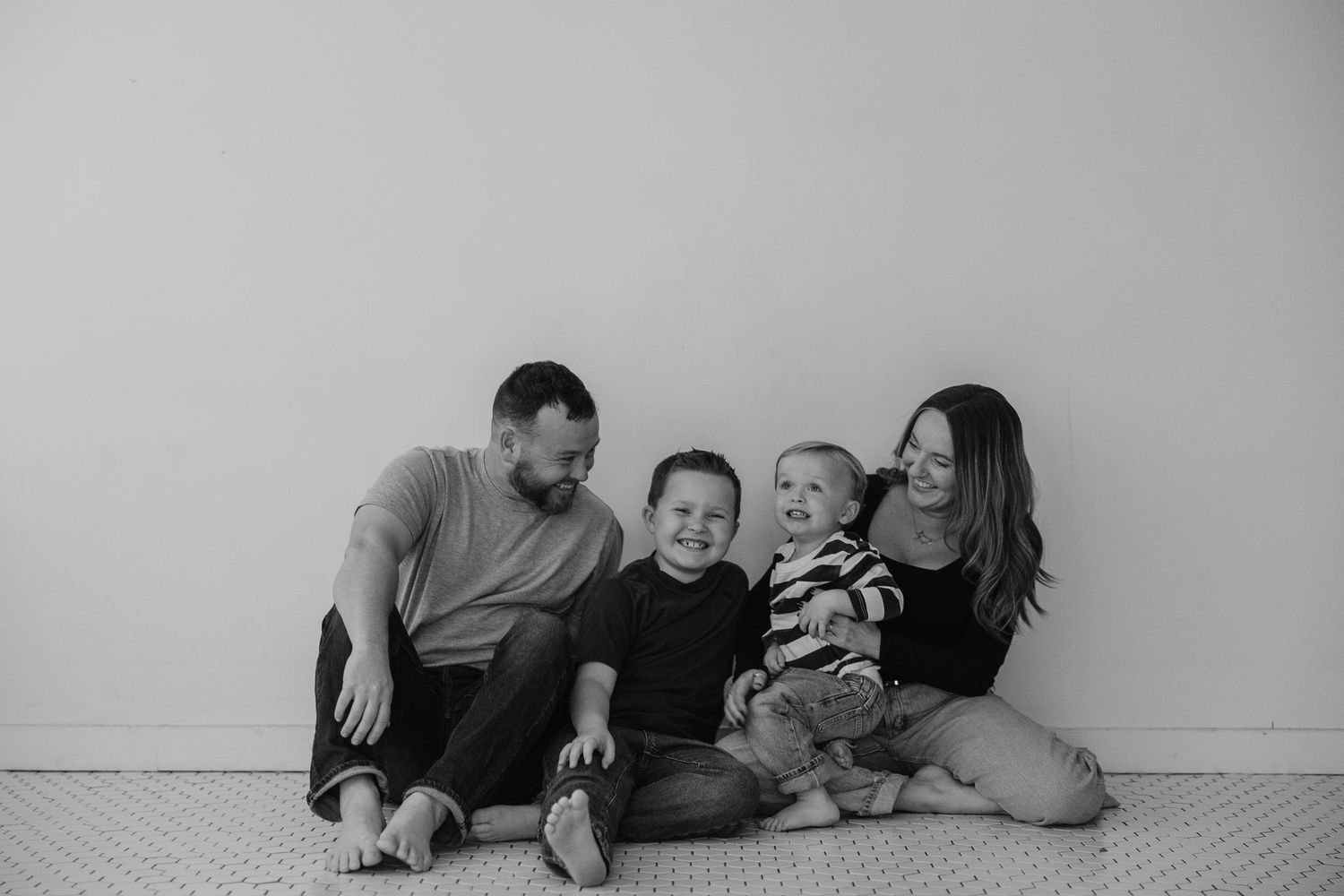 A black and white photo series showing a family relaxing and playing together on the floor.