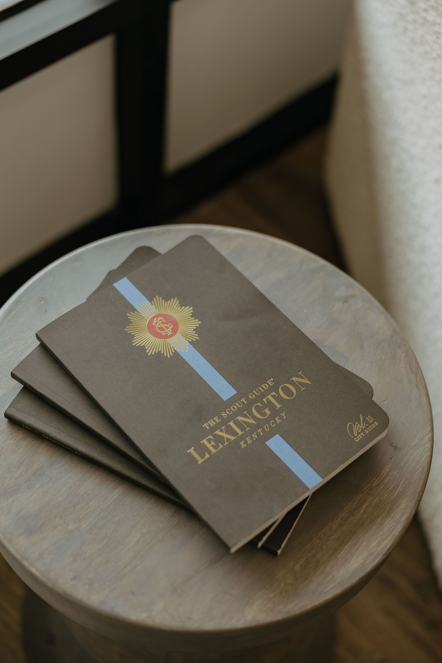 Brown leather notebooks with gold embossed Lexington logo stacked on wooden table.