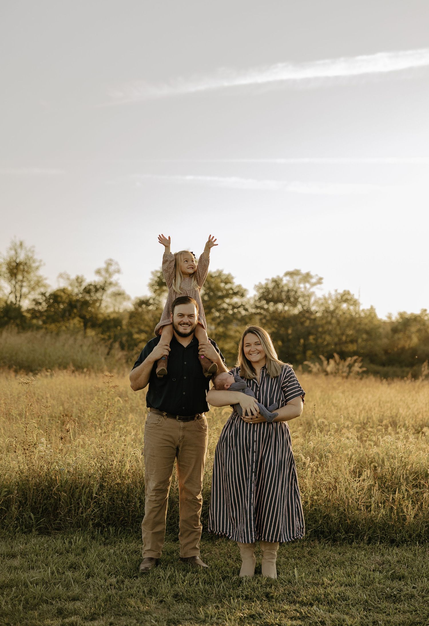 Friends celebrating joyfully in an open field during golden hour.