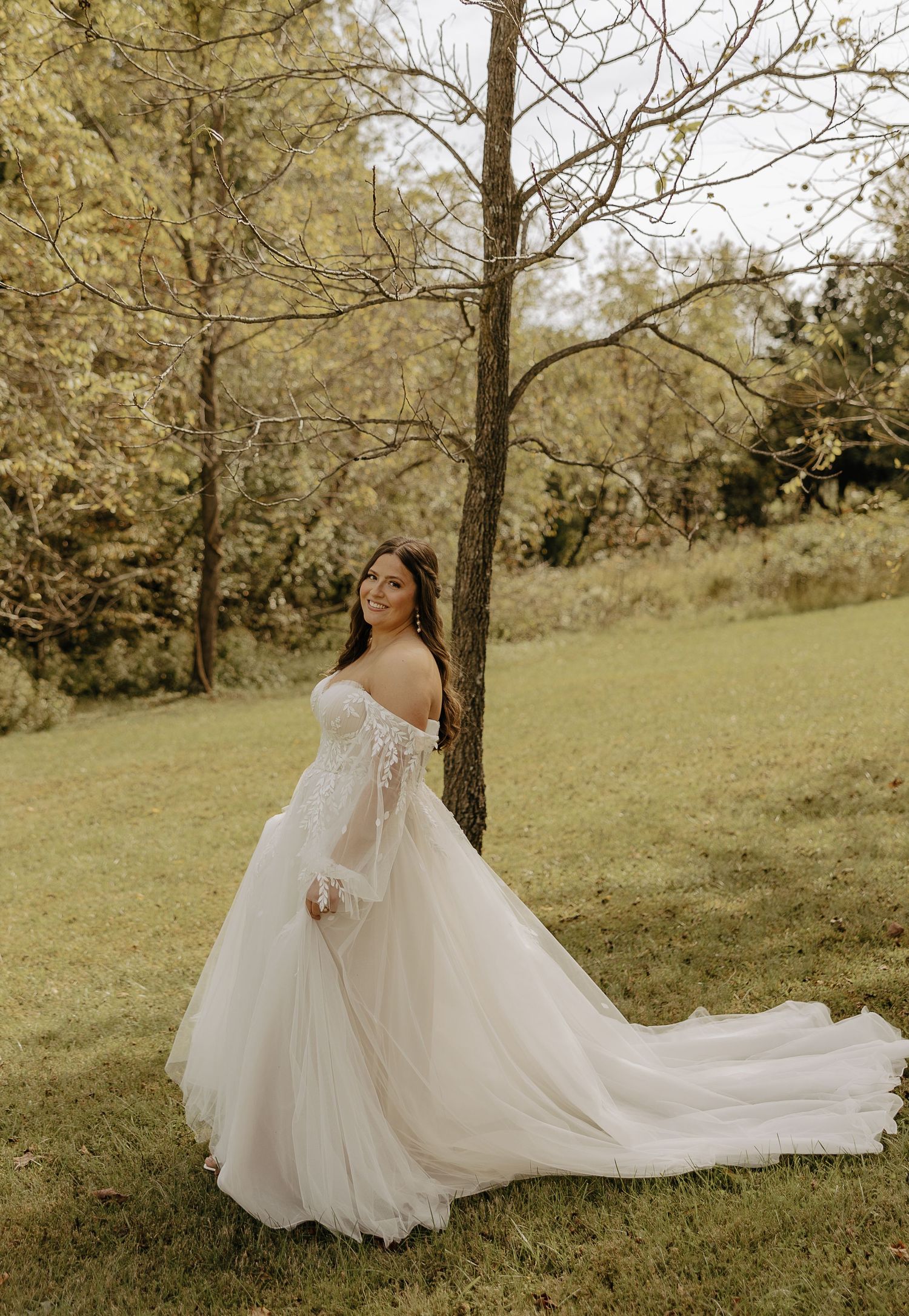 A flowing white wedding gown twirls gracefully in an outdoor autumn setting.