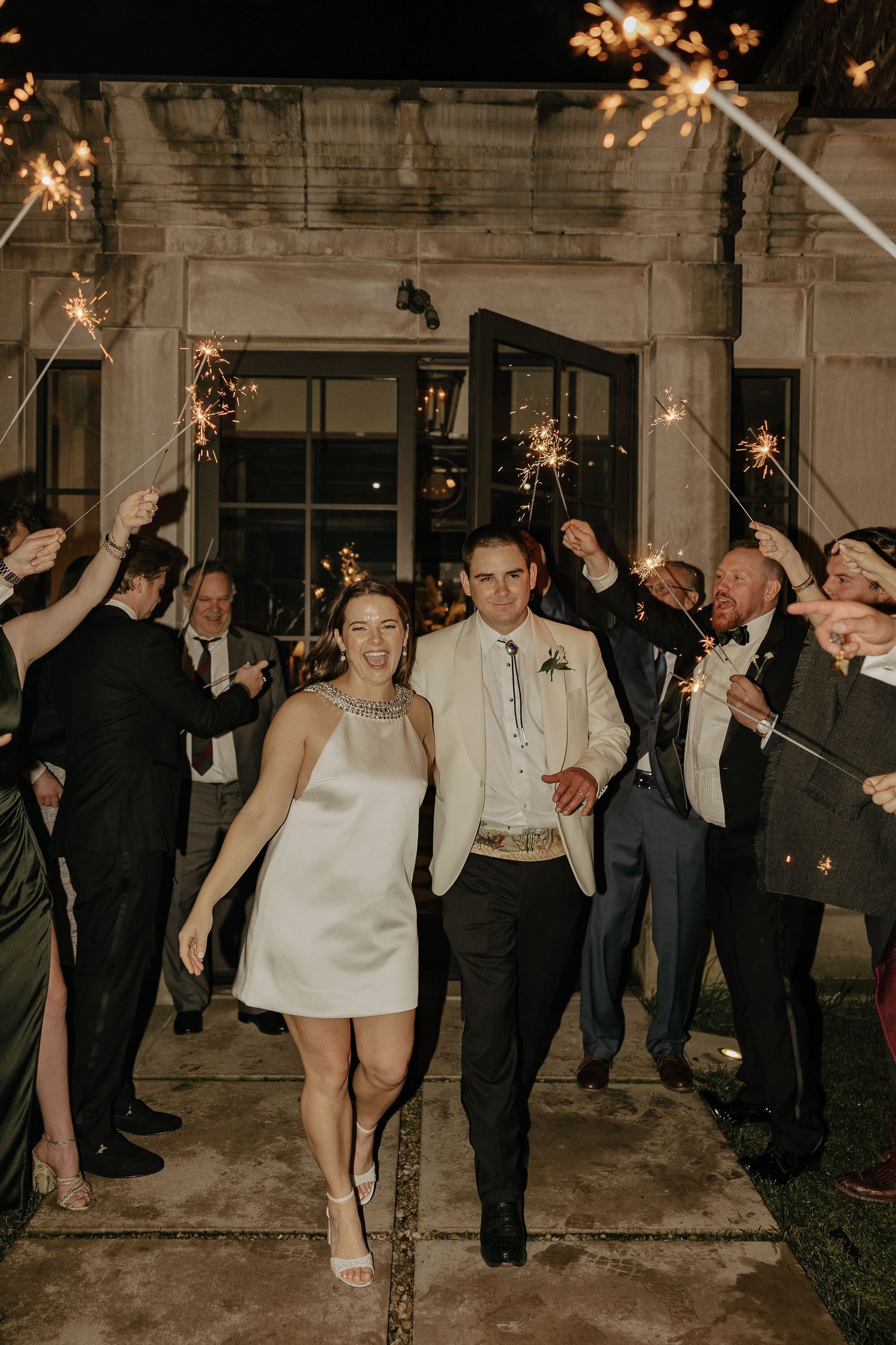 Wedding couple exits through sparkler sendoff line during evening celebration.