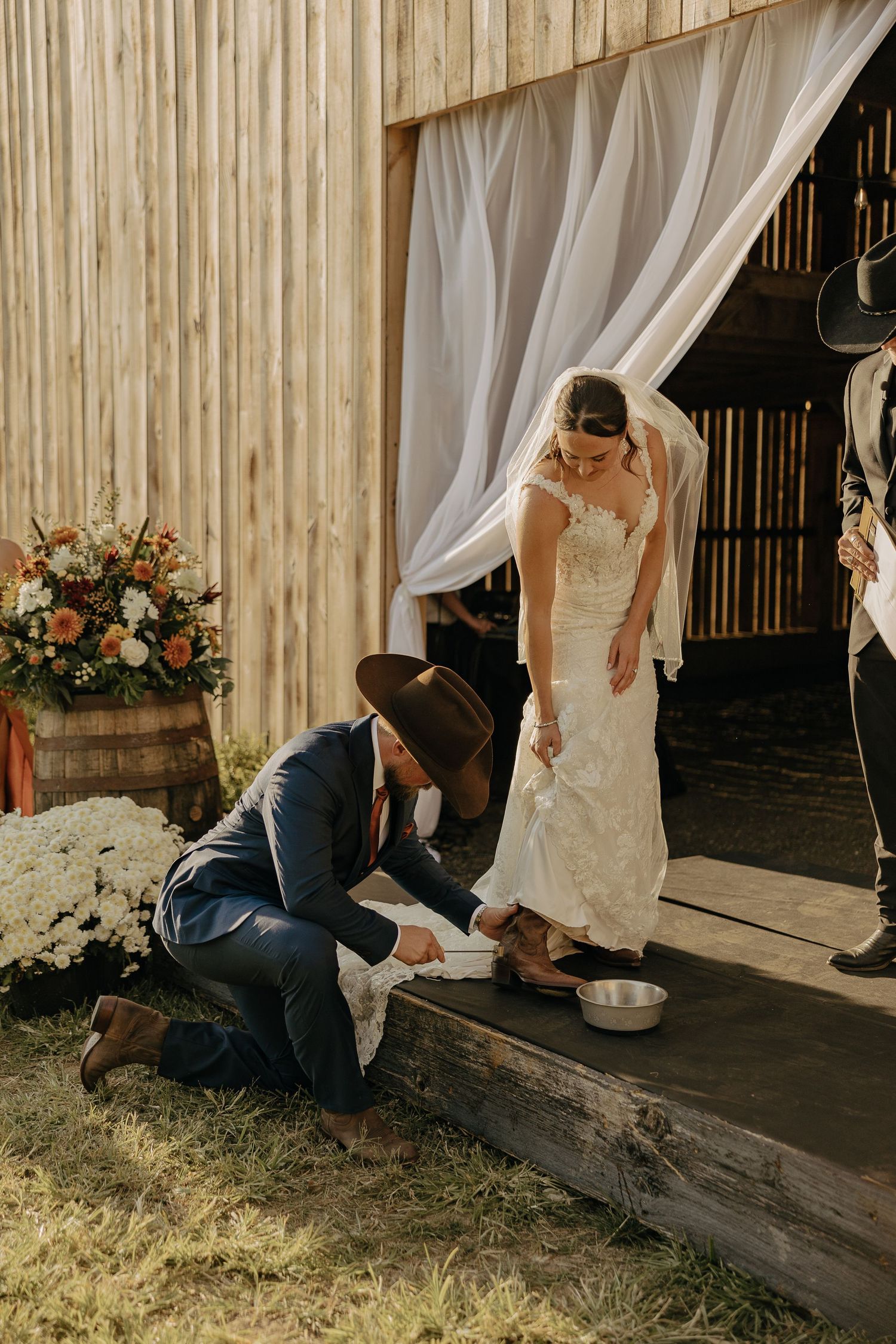 A couple shares a sweet moment with their dog during their rustic barn wedding ceremony.