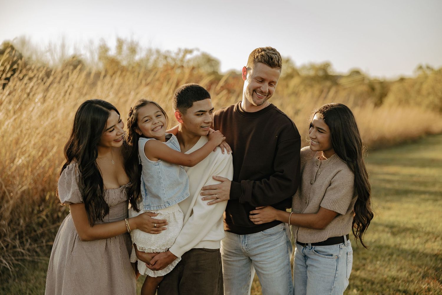 Family enjoying a sunset moment together in a golden field.