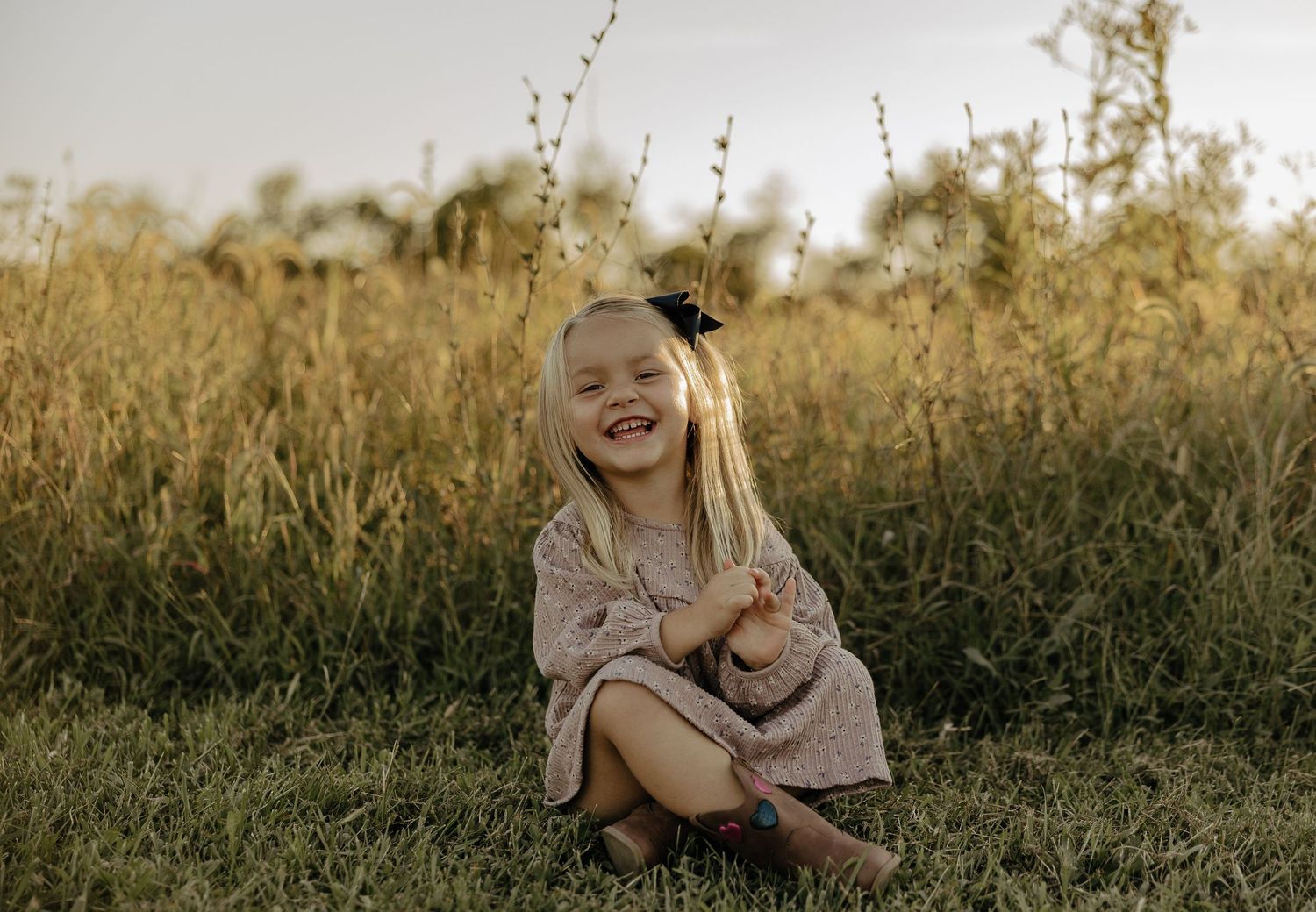 Child playing and laughing in a sun-drenched meadow during sunset.