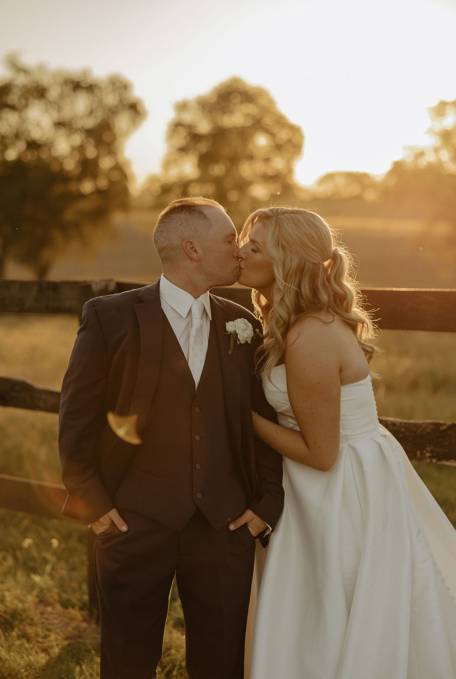 A couple shares a romantic sunset moment in formal wedding attire.