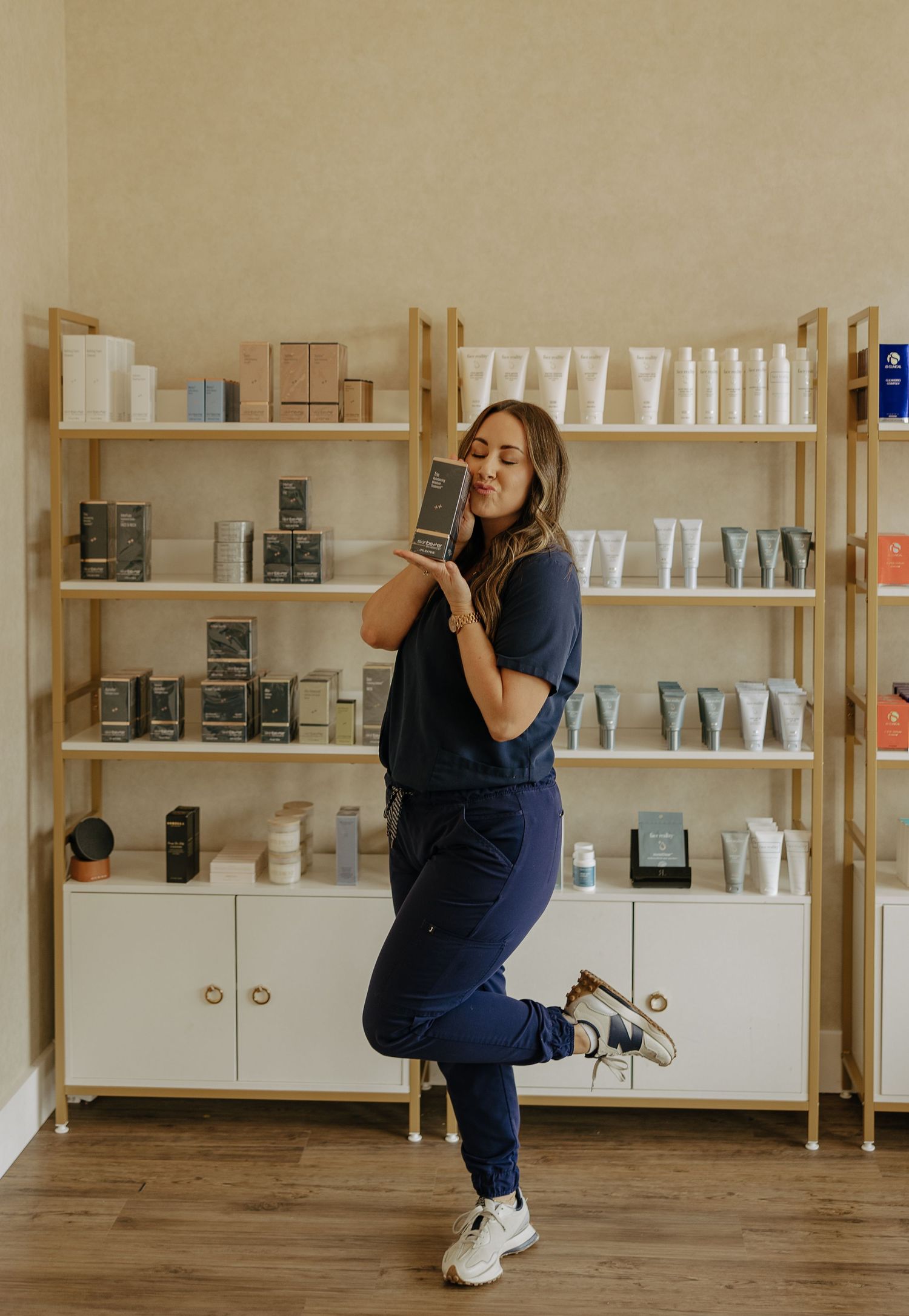 Person in navy scrubs demonstrating playful poses in a retail space with wooden shelving.