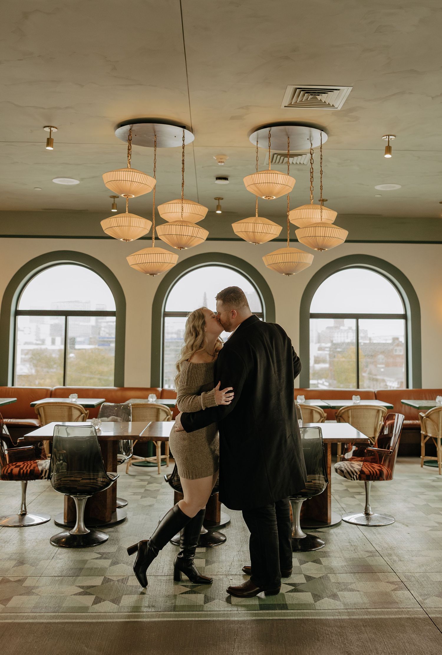 A couple dances together in a spacious restaurant interior with vintage-style pendant lights.