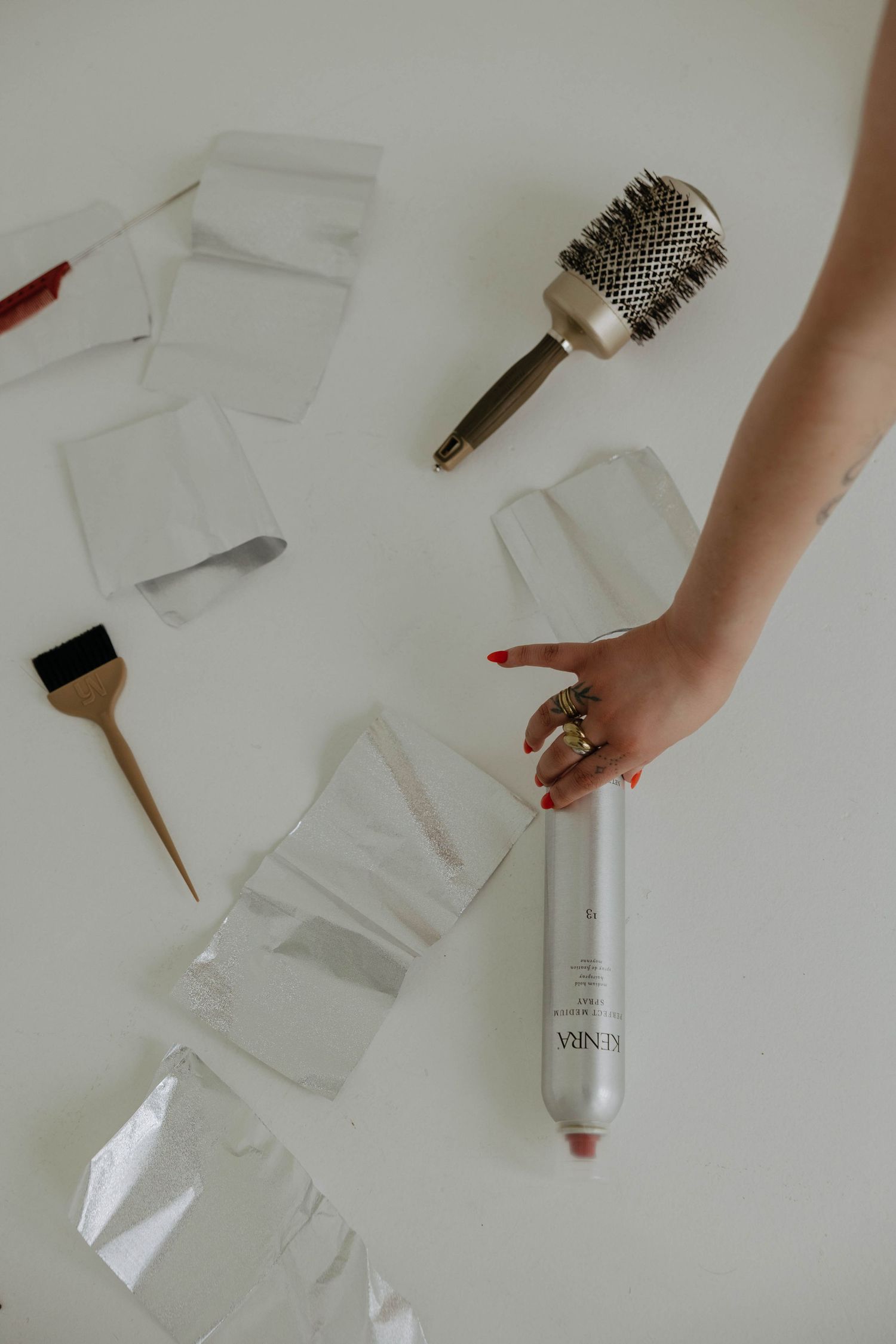 Beauty and hair styling tools including brushes and products arranged on a white surface.