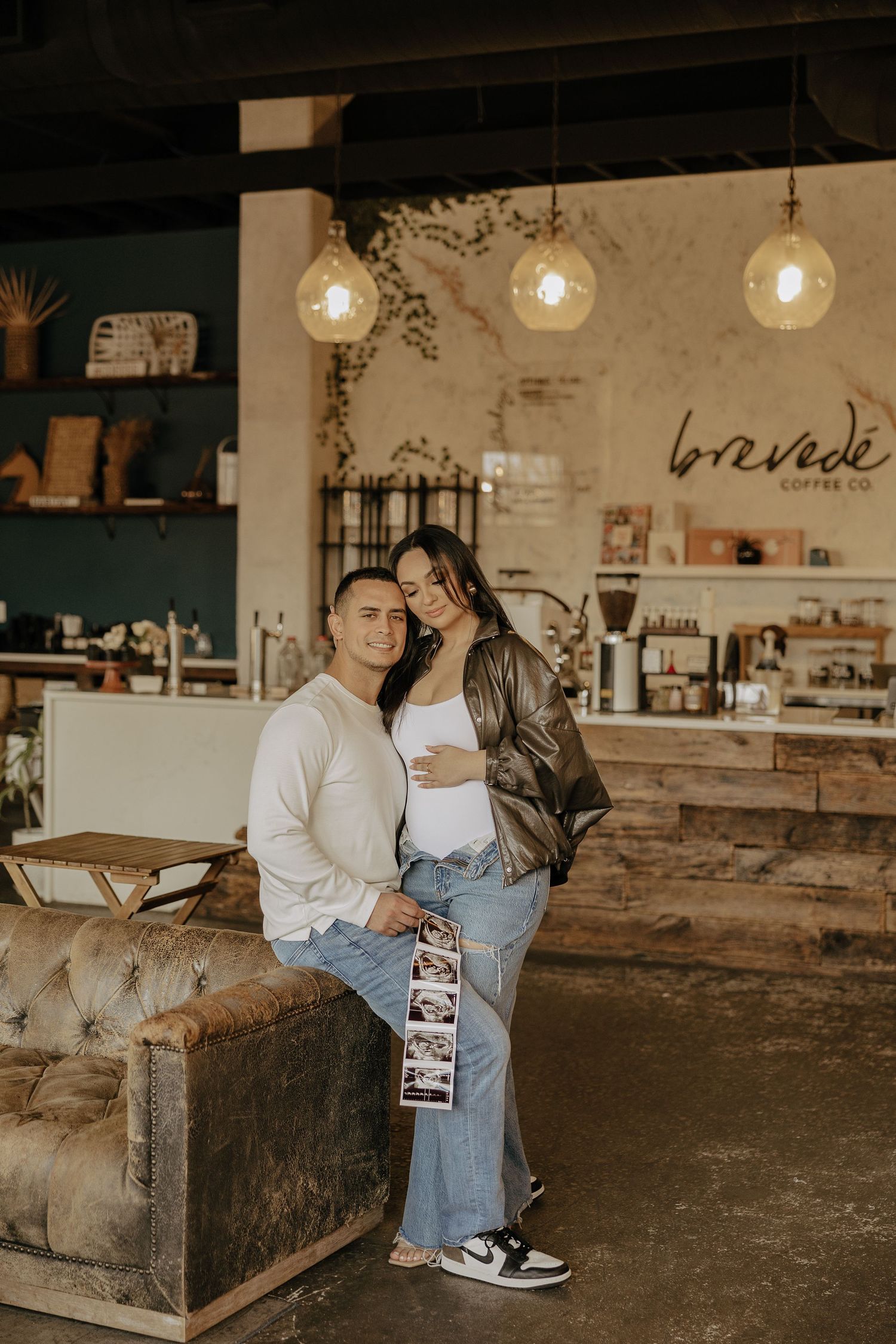 Couple sitting on rustic wooden benches in an industrial-style space with exposed lighting.