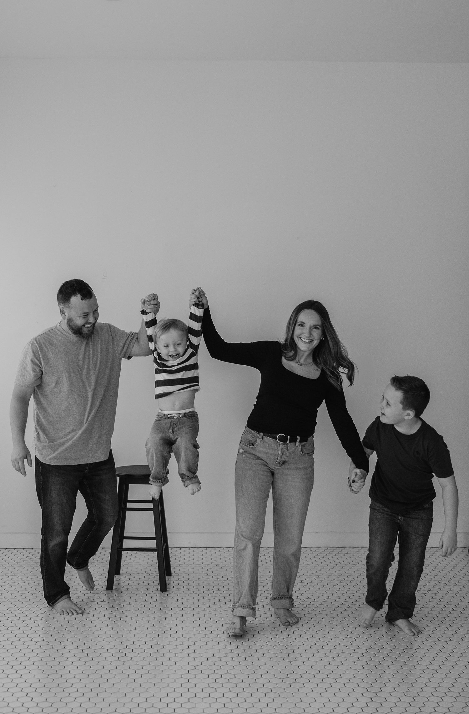 Black and white photo sequence showing a family walking and playing together on a carpeted floor.
