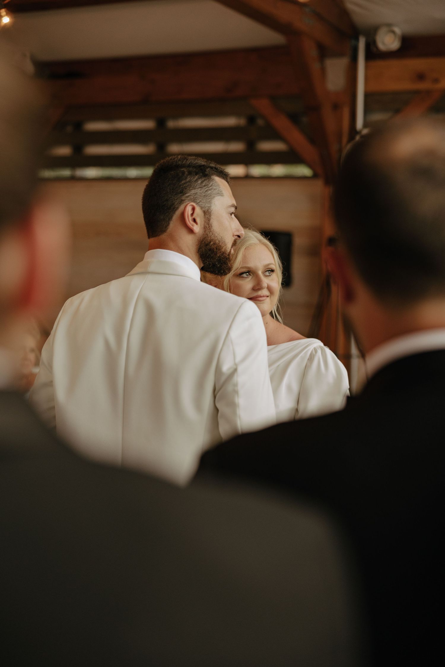 A group in formal attire stands together in a dimly lit venue.