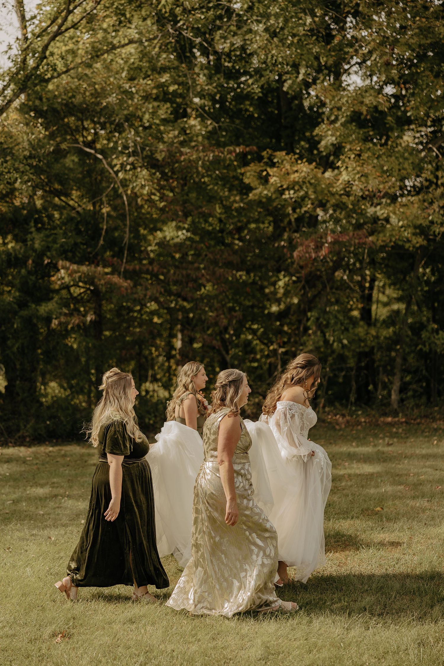 A group wearing dark and light dresses pose together on a grassy hillside.
