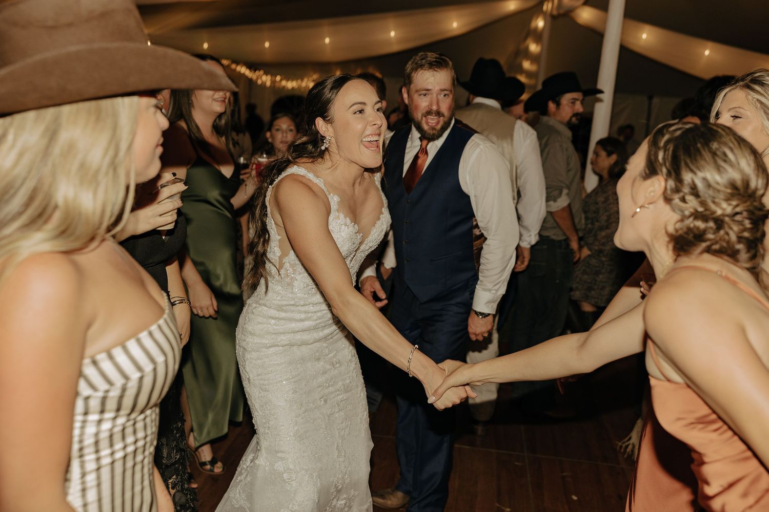 Wedding guests enjoy dancing and celebrating at a lively indoor reception.