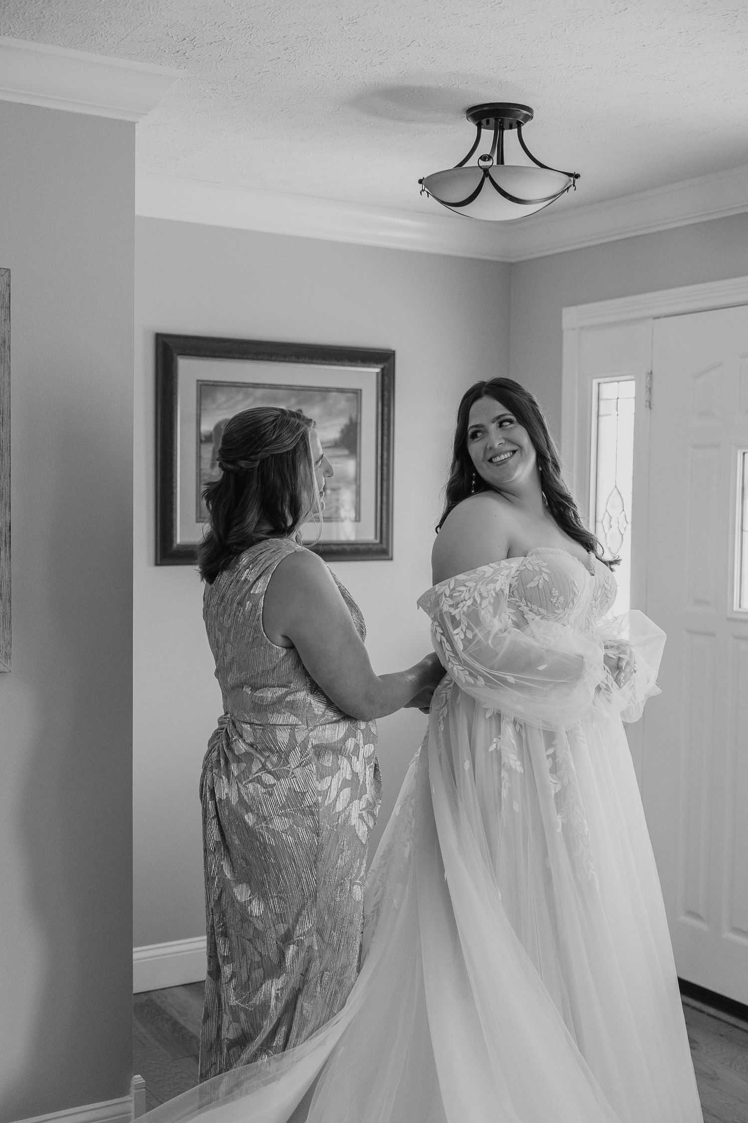 A wedding dress being prepared in a bright room with grey walls and white trim.