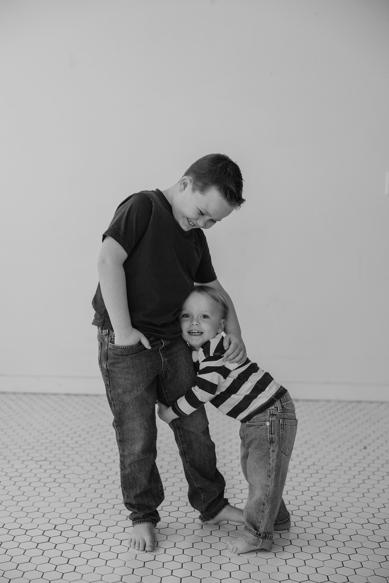A heartwarming black and white portrait of a playful embrace between parent and child on a patterned floor.