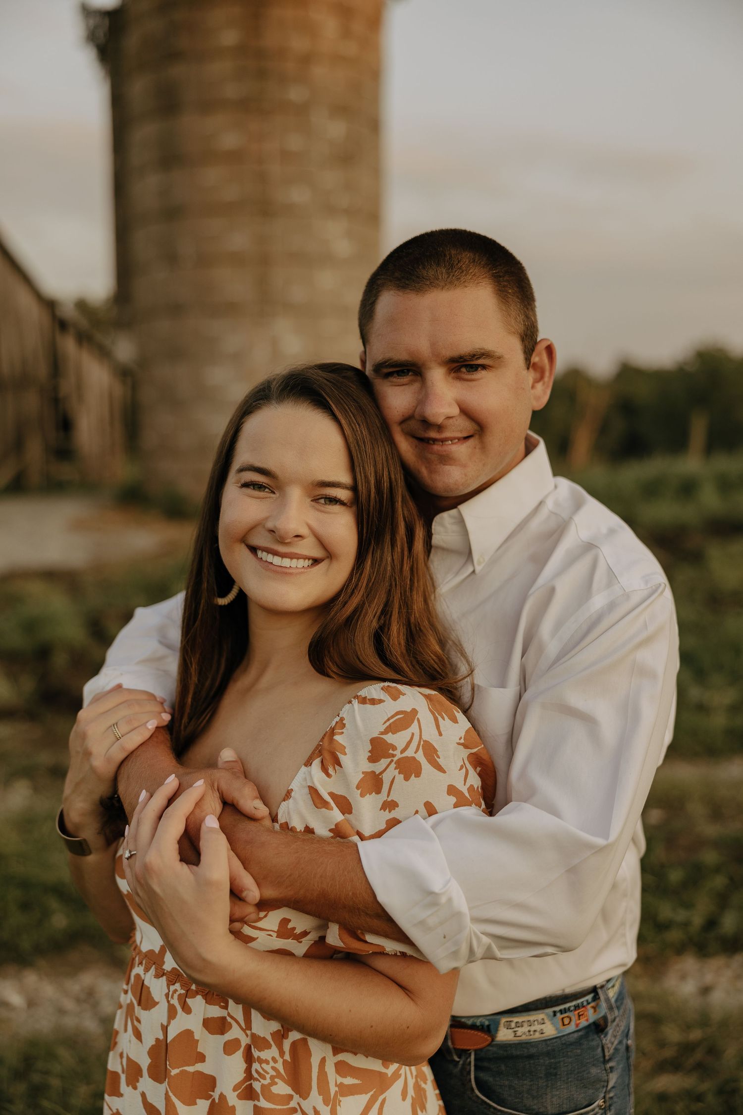 Sweet embrace captured near rustic silo during countryside photo session.