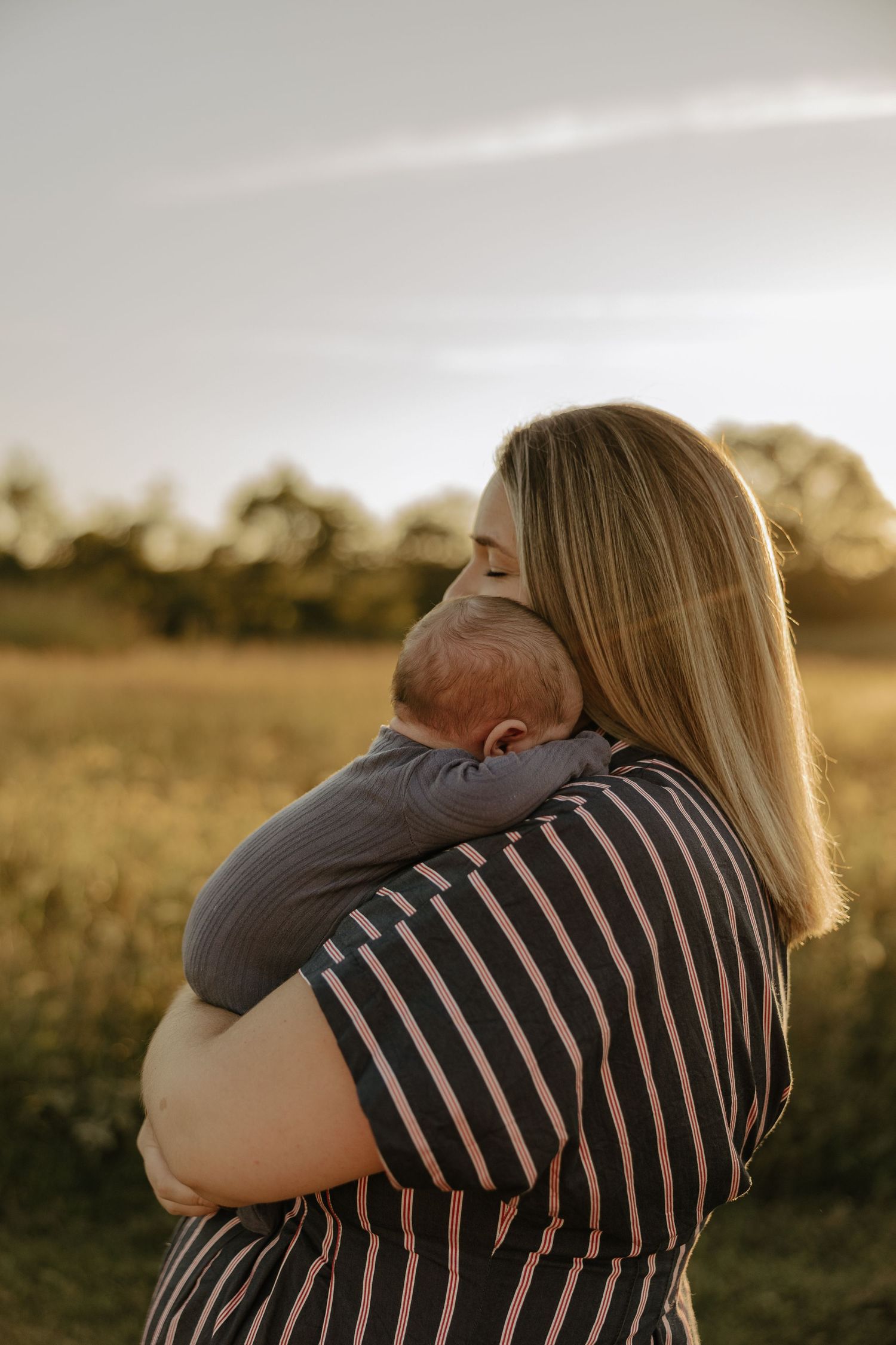 Couple embraces tenderly in a golden field during sunset.