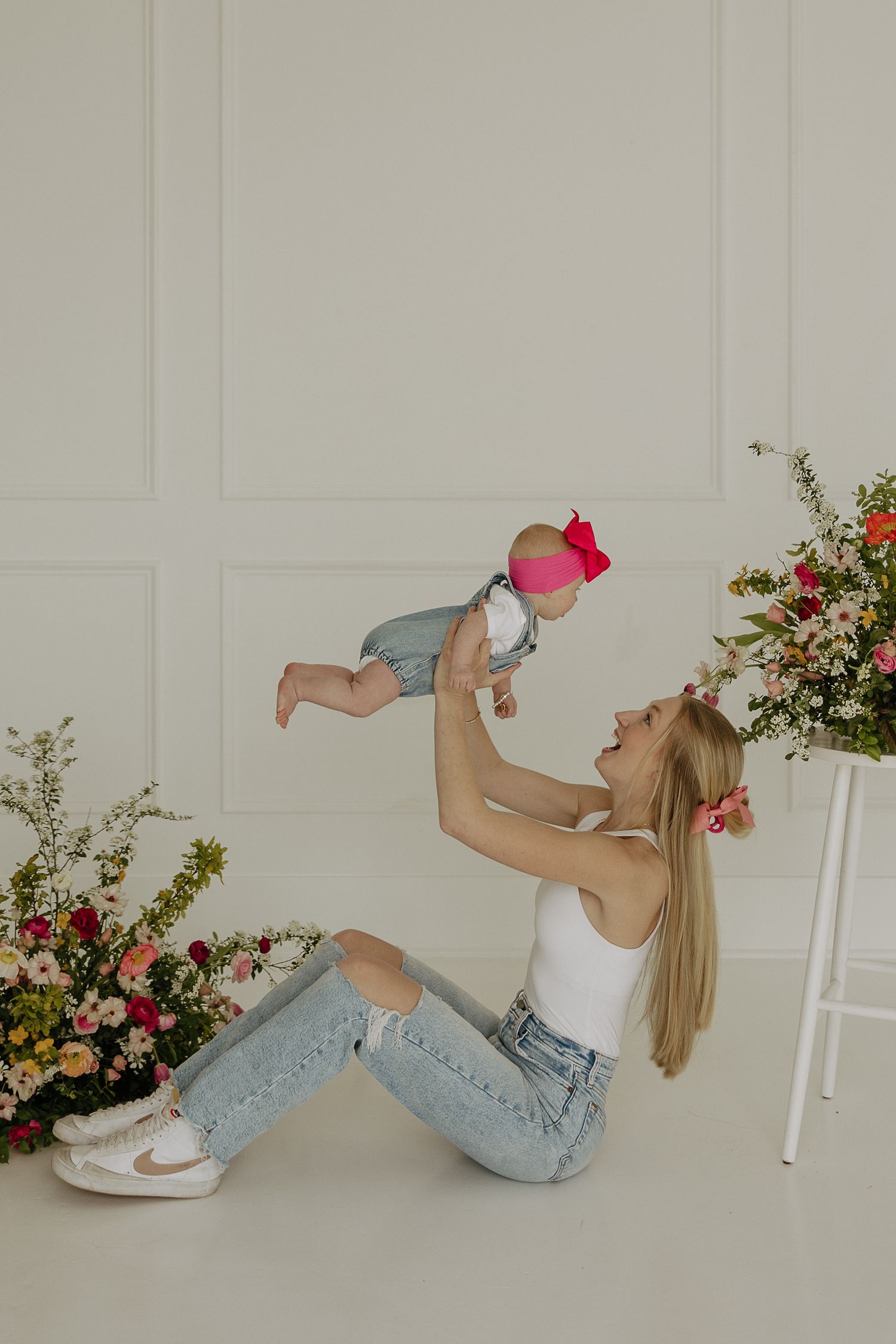 A playful photo series showing a white tank top and light jeans against a neutral wall with colorful flowers.