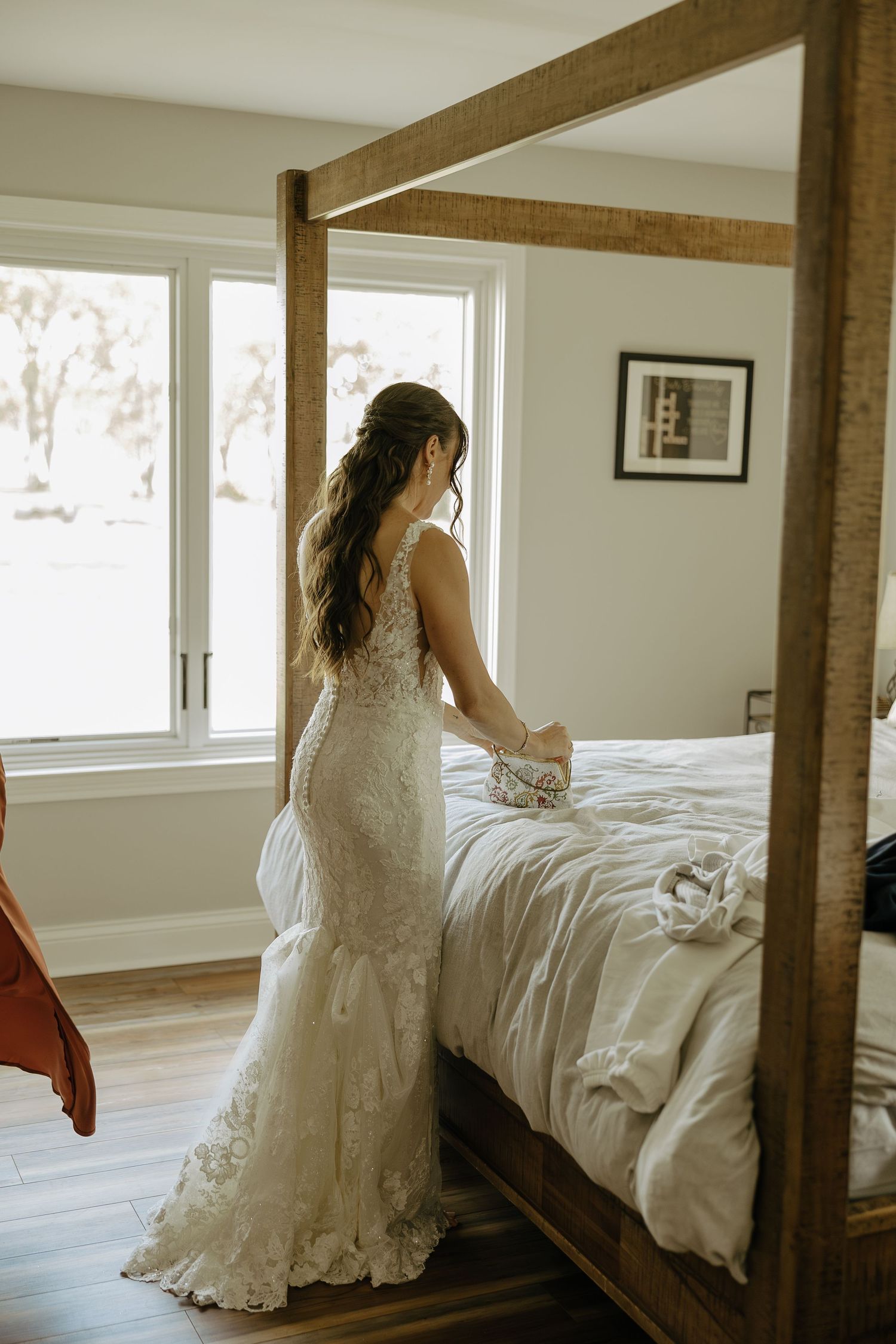 A wedding dress with intricate lace details photographed against a bright, modern bedroom setting.
