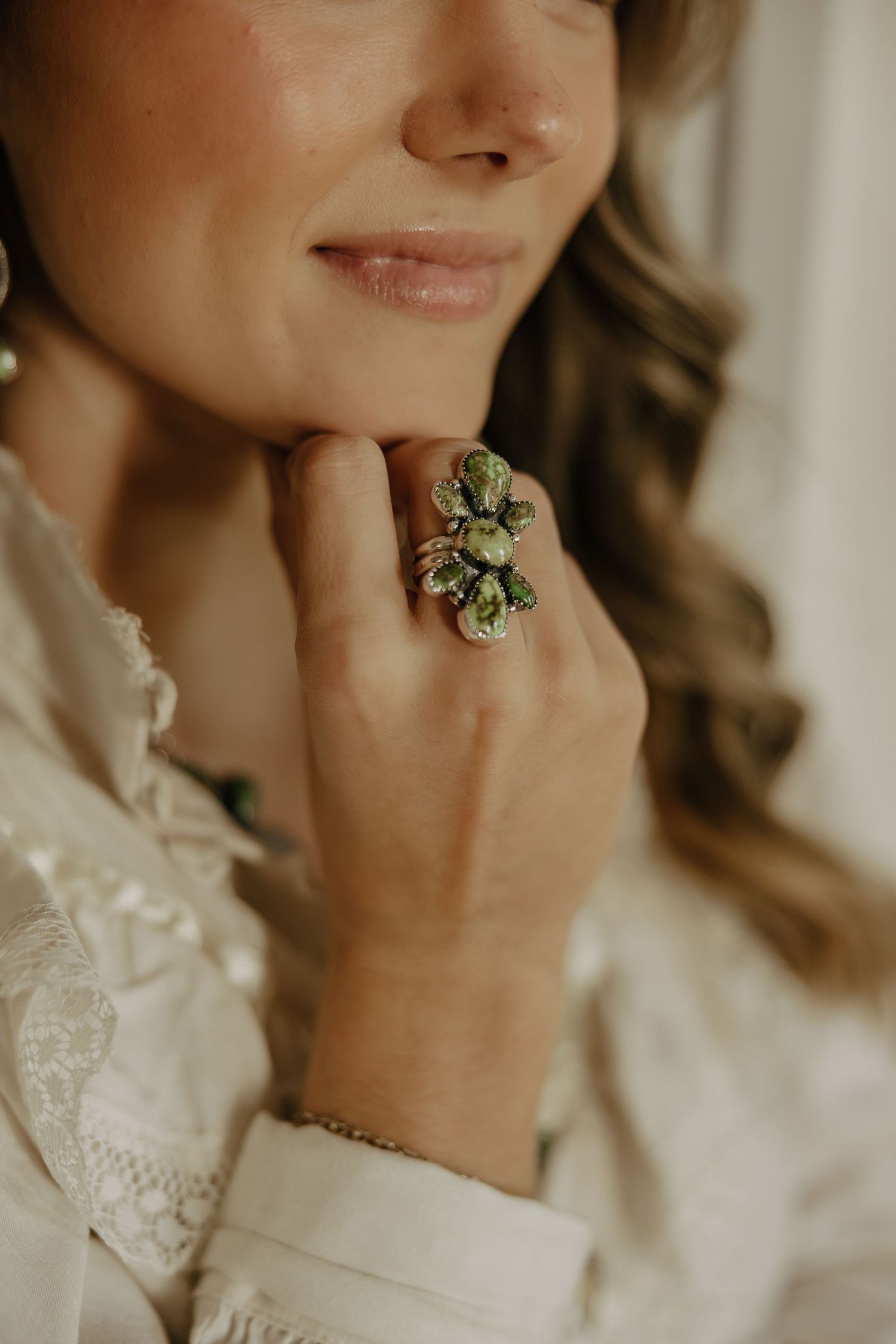 Close-up detail of hands and jewelry against a soft neutral background.