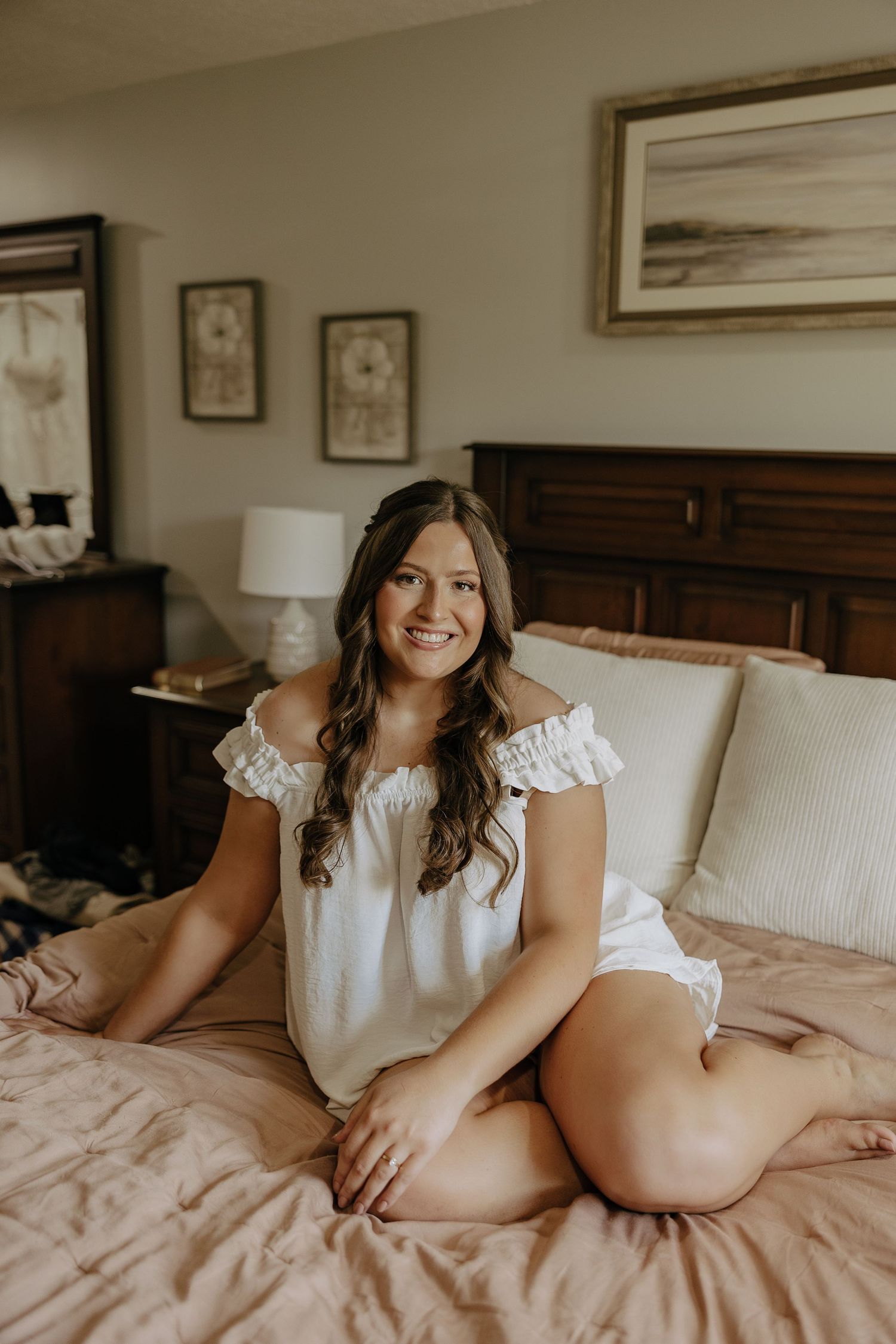 Intimate boudoir photography session featuring soft lighting and delicate white lace details on a pink bed.