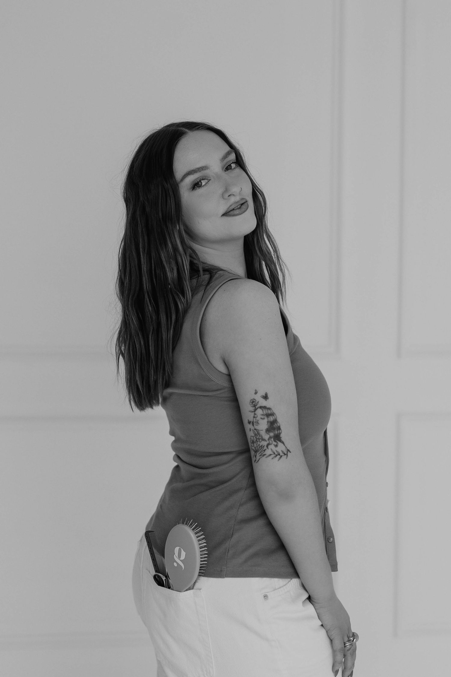 Professional in olive tank top showing tattoos in artistic black and white portrait.