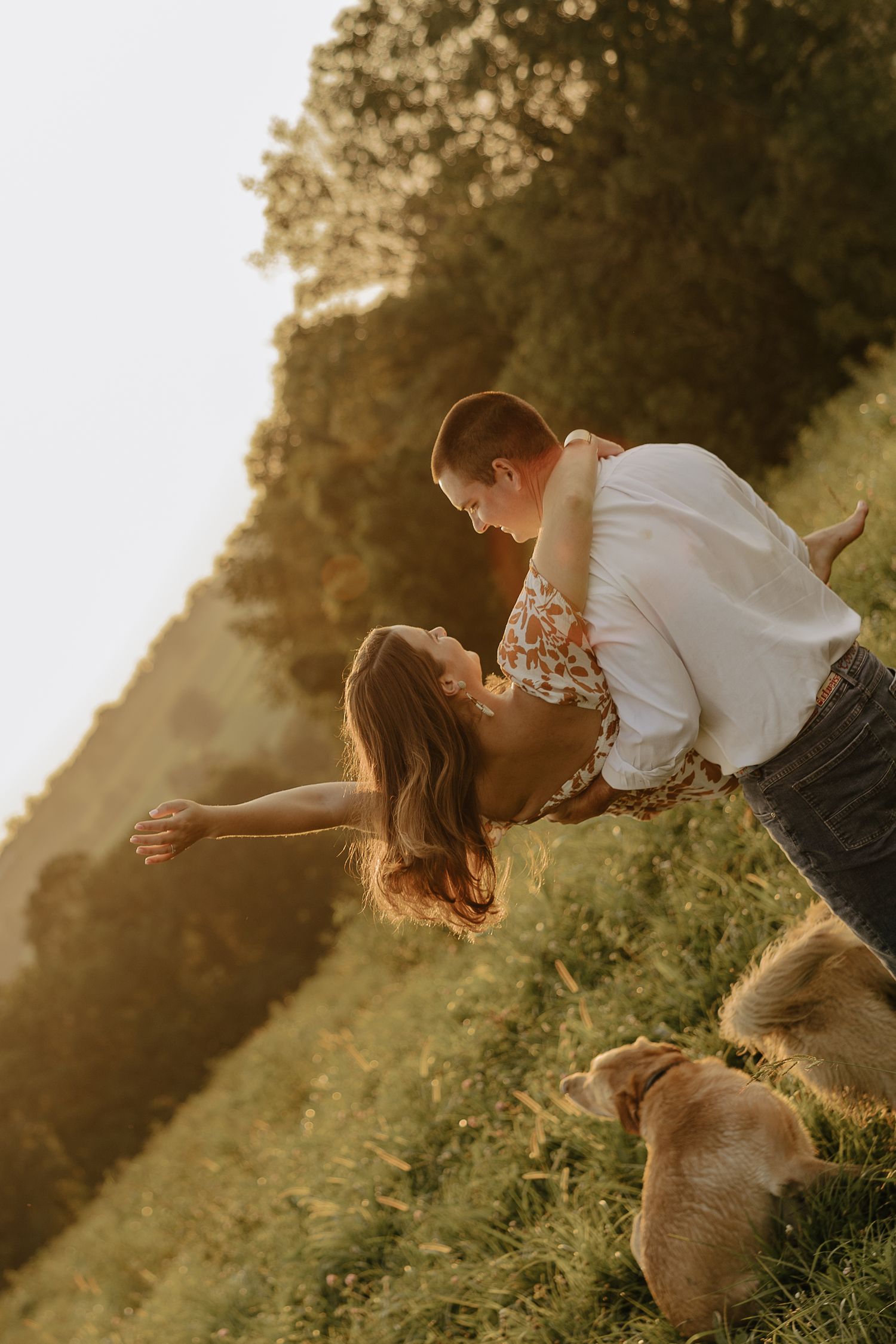 Couple shares romantic moments in a sunlit field during golden hour photography session.