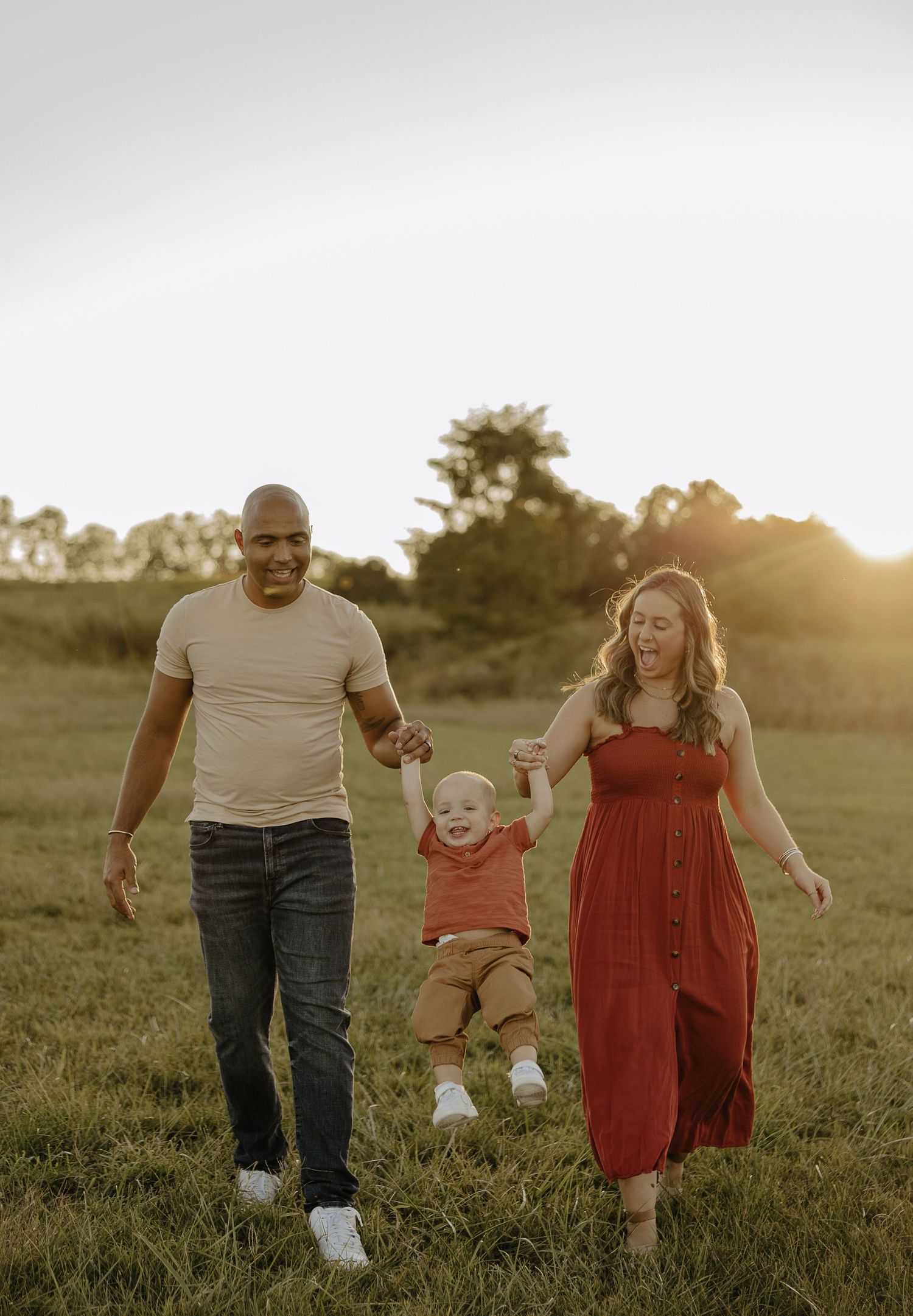 Family walking together through grass field during sunset.